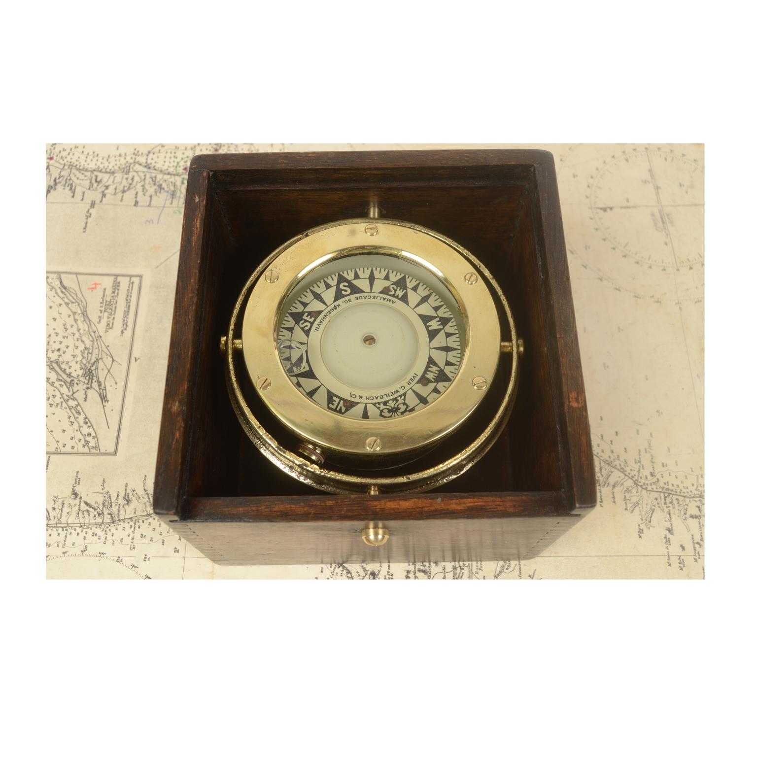 Nautical compass of brass and glass mounted on a universal joint and placed in its original oak box signed Iver C. Weilbach & C. Amaliegade 30 Copenhagen, made in the late 19th century. The compass is made up of a cylindrical vessel of brass and