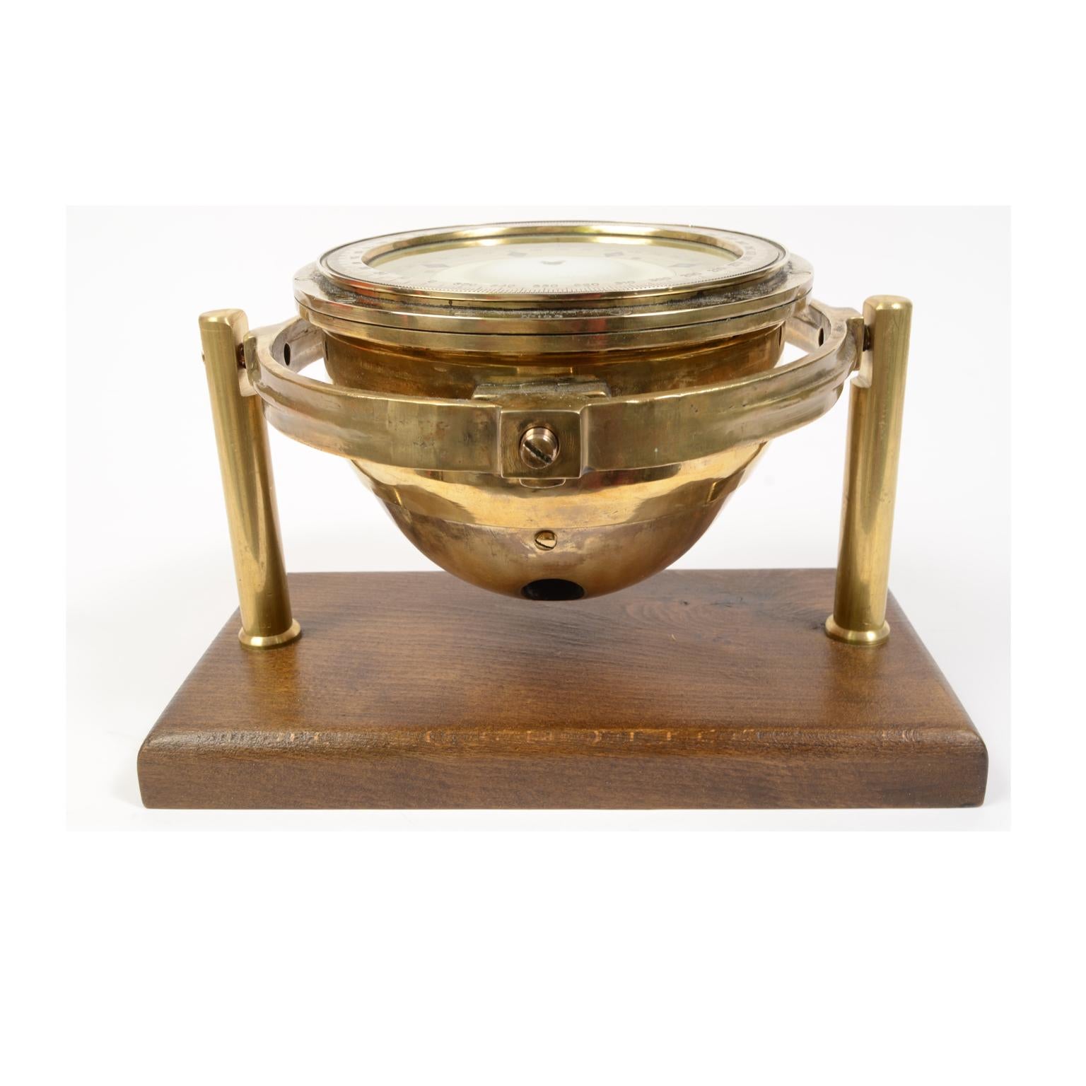 Liquid nautical compass of brass and glass made in the early 1900s, mounted on a universal joint and mounted on a walnut wood board with custom-made brass supports. Complete with double goniometric circle, both external, of engraved brass, and on