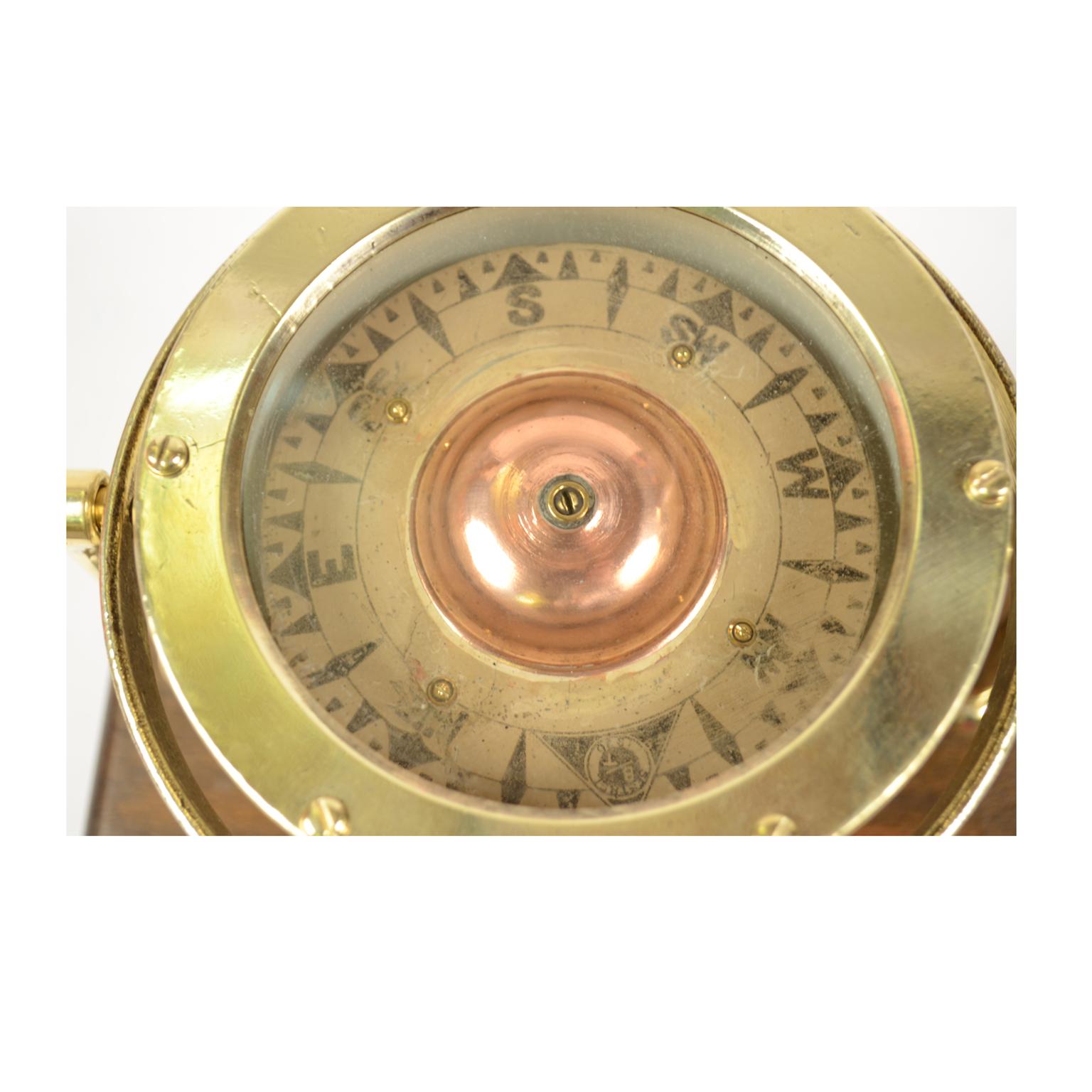 Nautical liquid compass, brass, on universal joint, British manufacture, mounted on wooden board. The compass is signed Sestrel BT 1876 the compass has a cylindrical brass container, on the bottom of which a stem of hard metal is fixed, on which