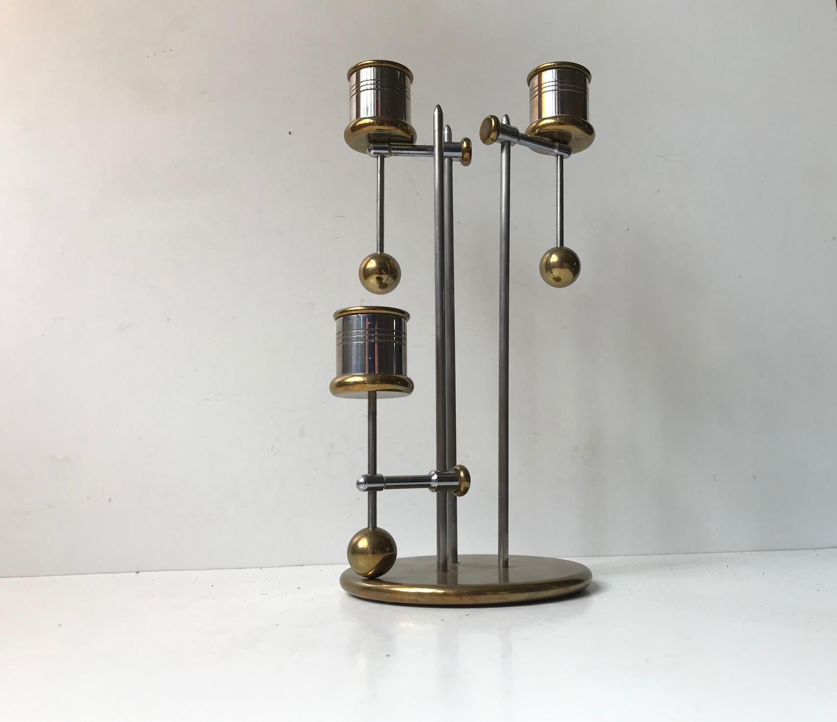 Adjustable and counterweighted candlestick in brass and stainless steel by Peter Seidelin Jessen for Delite. Suspension and counterweight mechanisms allows you to adjust the heights of the 3 arms and make sure that the candles do tilt over when you