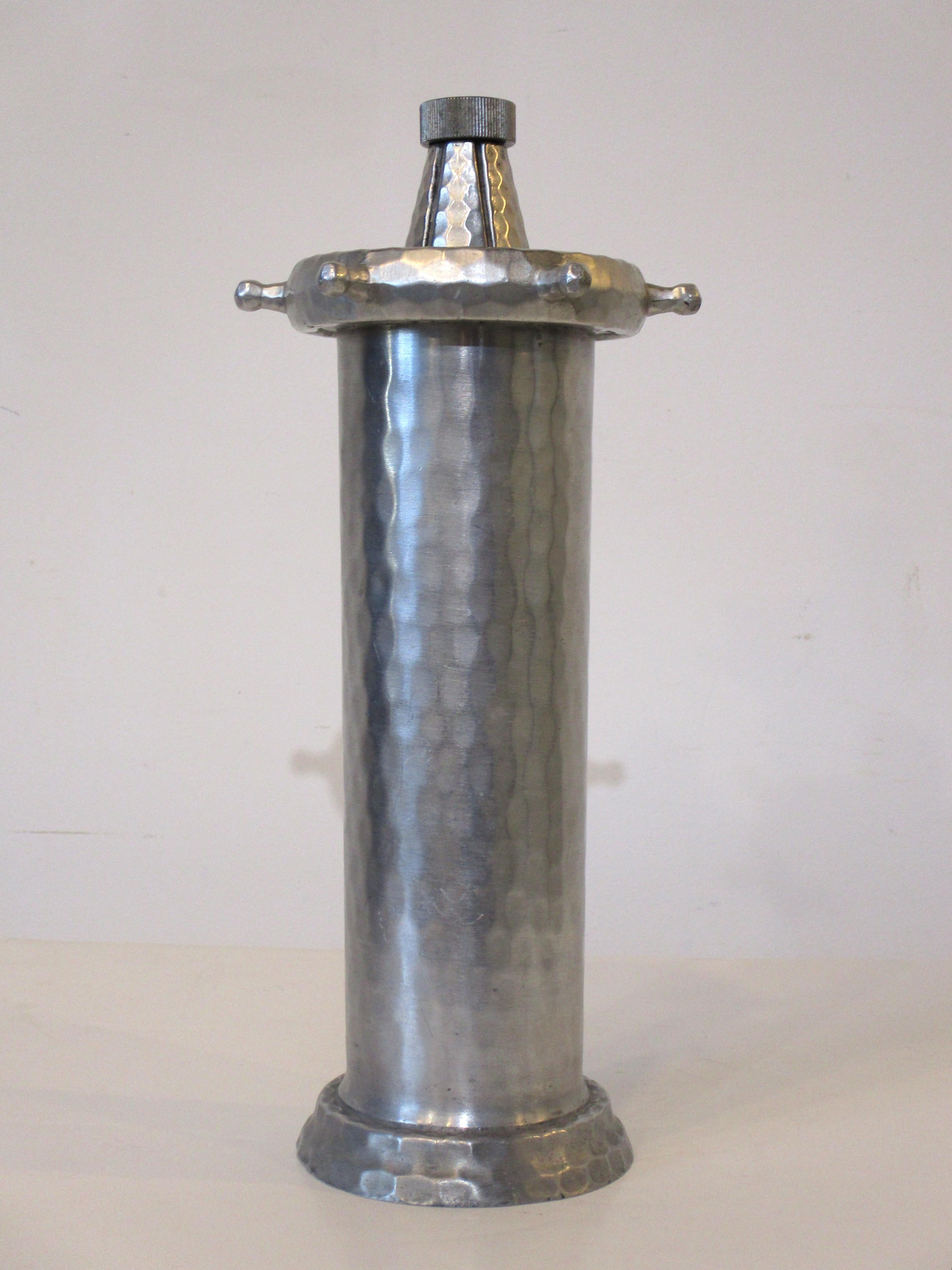 A hand forged hammered aluminum nautical themed cocktail shaker with the top as a ships wheel with three boat anchors. The wheel top screws off for liquids and it has a cap with built in strainer for pouring manufactured by the Everlast Metal