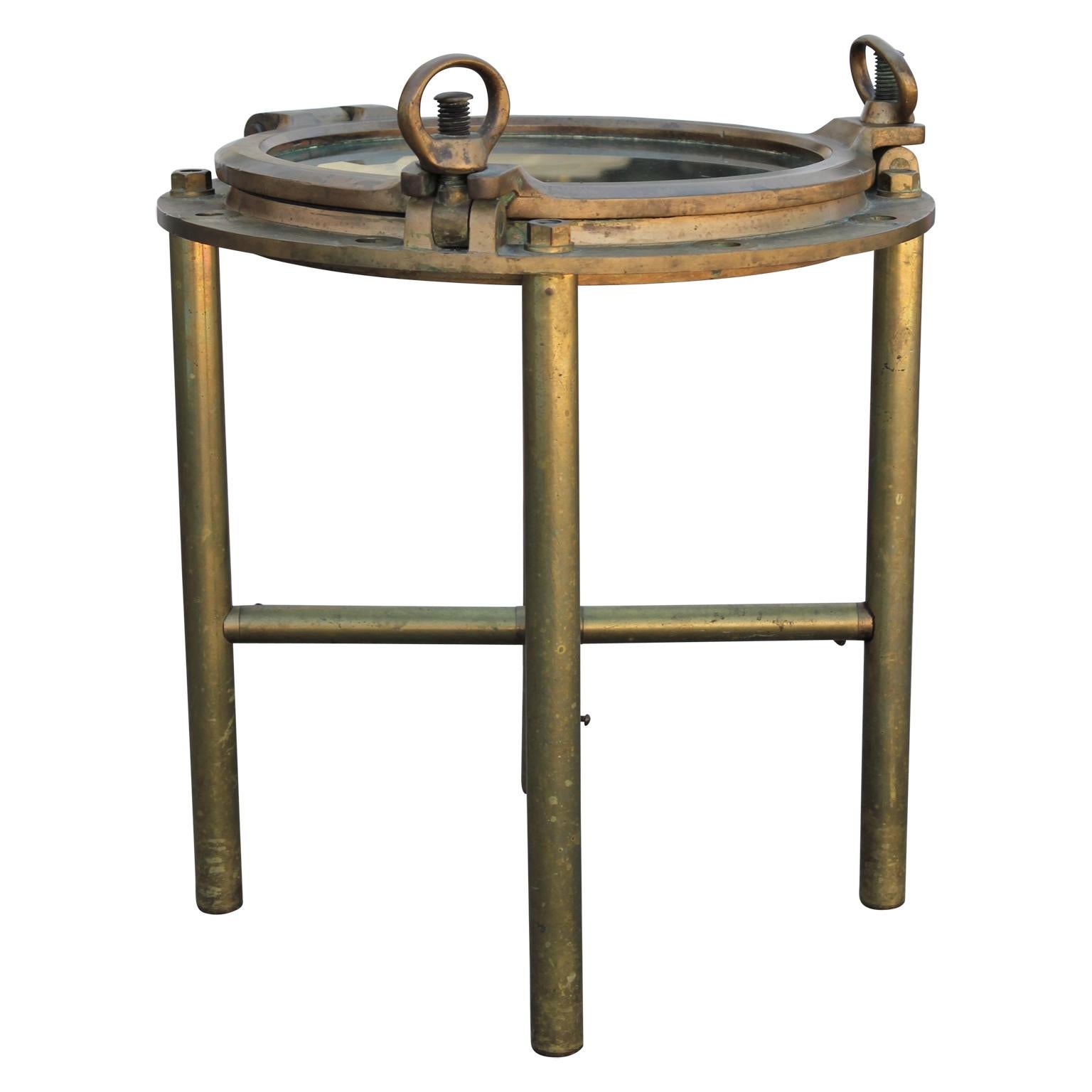 Stunning nautical modern brass heavy round porthole window side table. The porthole screws work as they should. Well crafted and has the perfect patina.