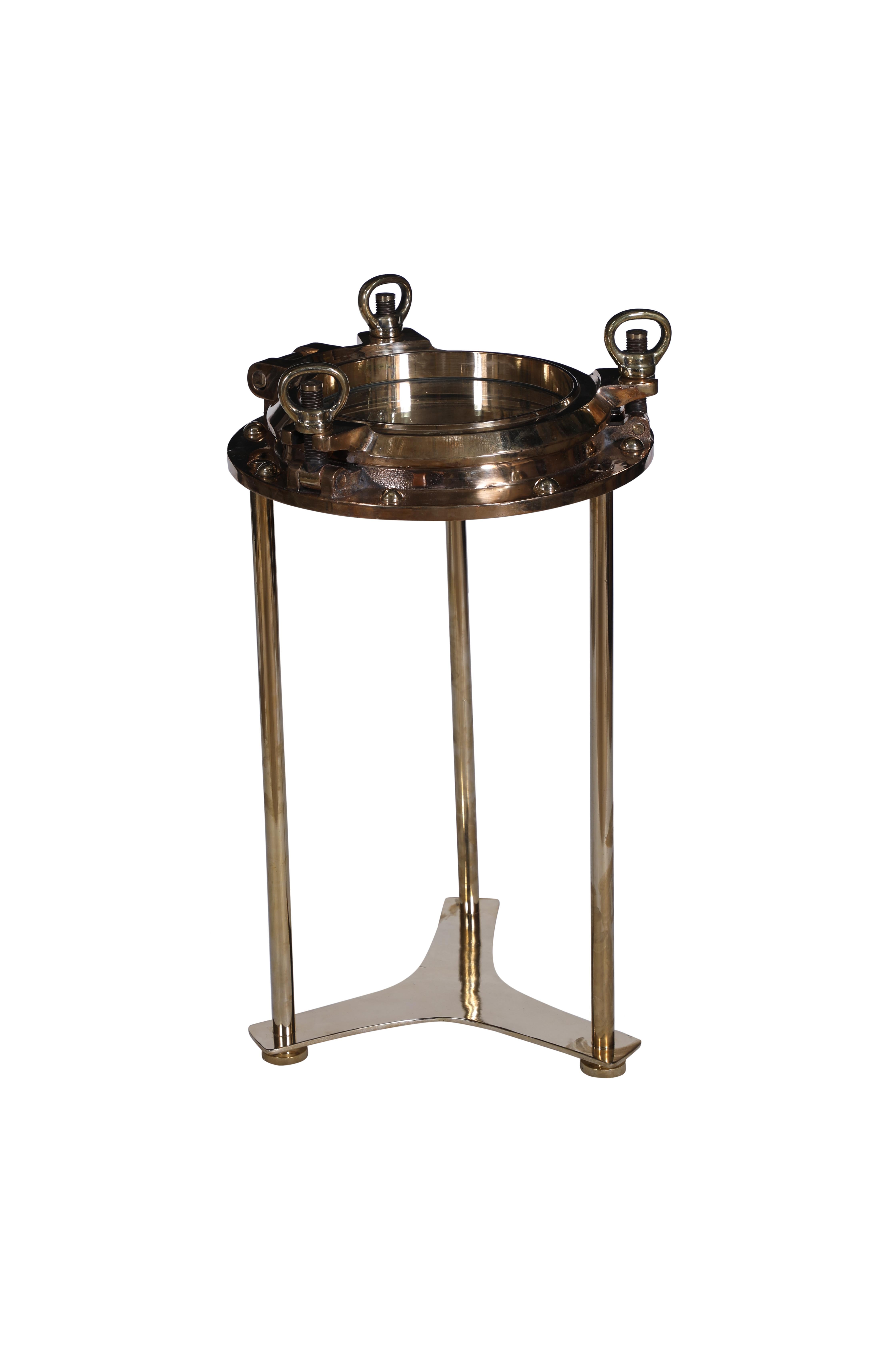 A bronze ship's porthole converted to a side table by Deborah Lockhart Phillips. It has been designed to come apart leaving the porthole free of the legs and base. The rivets have been put back in as these come out when taken off the ships. The