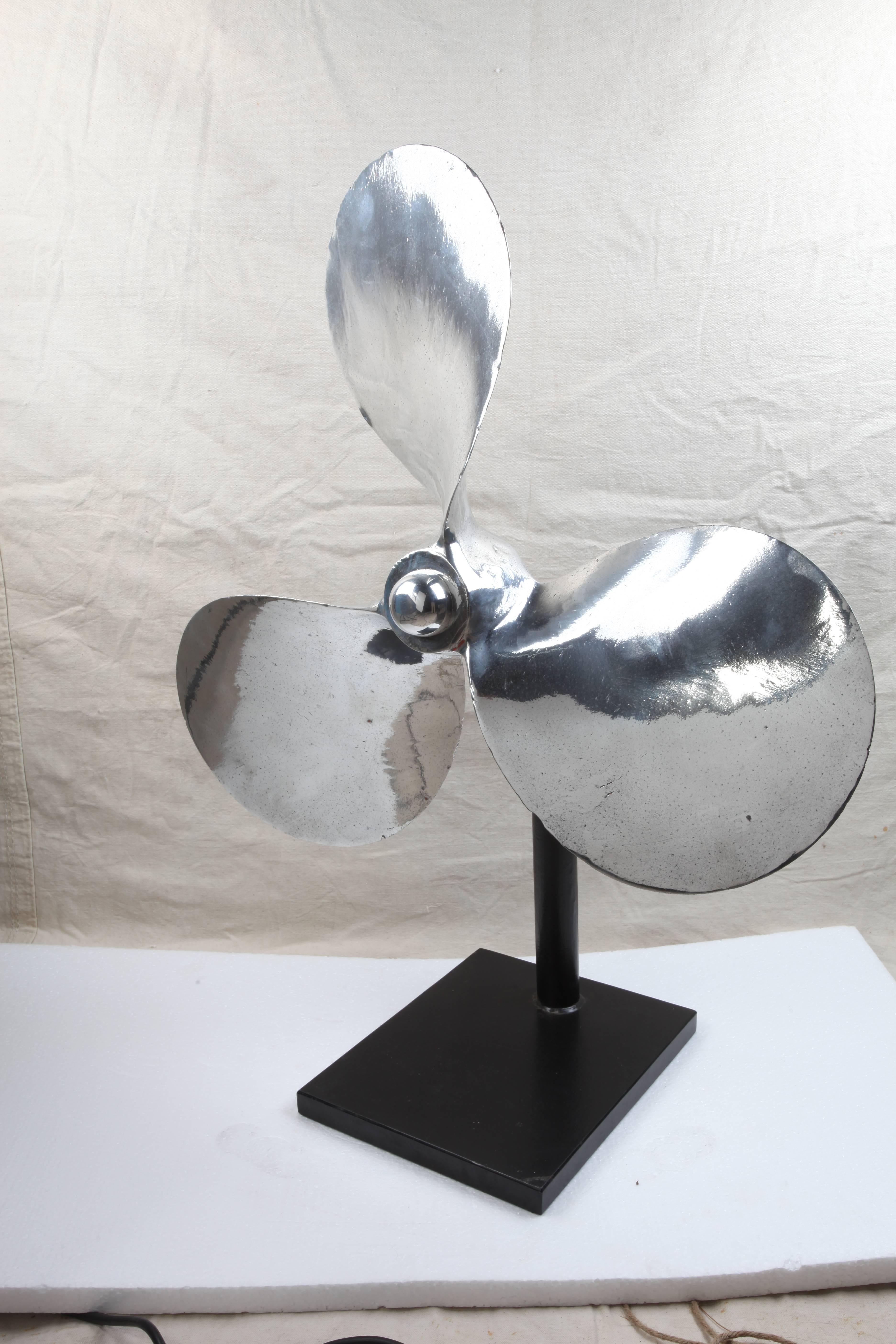 A very large chrome ship's propeller from a large lifeboat, circa 1970s. It sits on a custom made stand made of iron. Can be taken on and off. The rounded nut holding the prop onto the stand is chrome. Makes a great sculpture, inside or out.