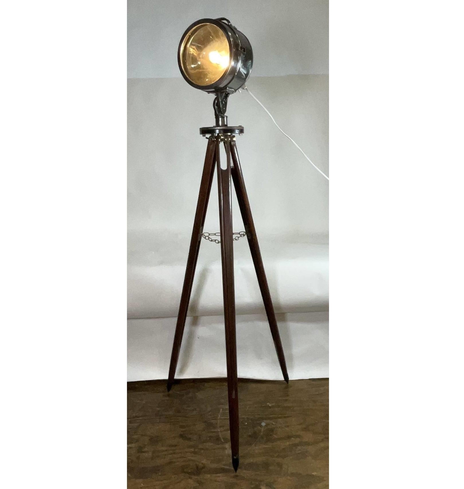 Projecteur de bateau du début du 20e siècle. Projecteur de bateau avec tête en acier poli, poignée de réglage, objectif de 10 pouces de diamètre, monté sur un trépied en bois. Hauteur totale : 76