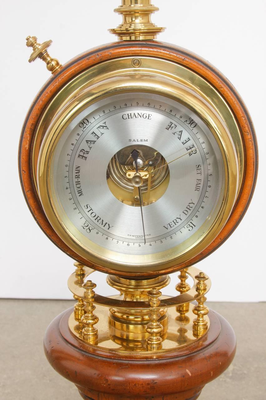 Monumental brass table lamp by Stiffel featuring a nautical style clock and barometer 360 degrees on a brass column. Each side is encased in beveled glass with a winding key for the face of the clock. The lamp has a tall brass column ending with a