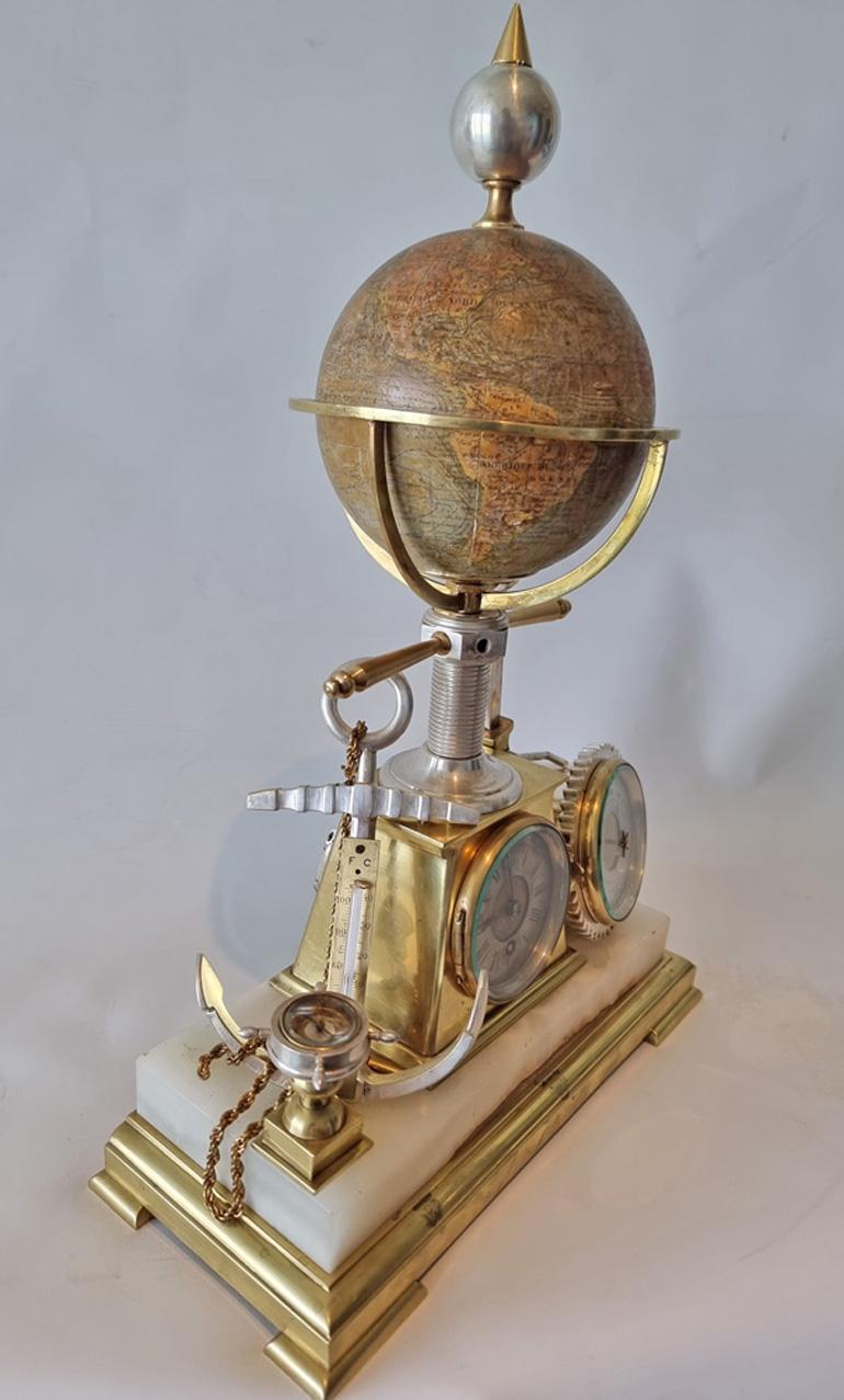 A combined timepiece, weather station and globe desk piece industrial clock. Constructed of onyx and silvered and gilt bronze. The white onyx base with timepiece in shaped bronze case, and rotating globe above, the dial with gilt bronze centre and
