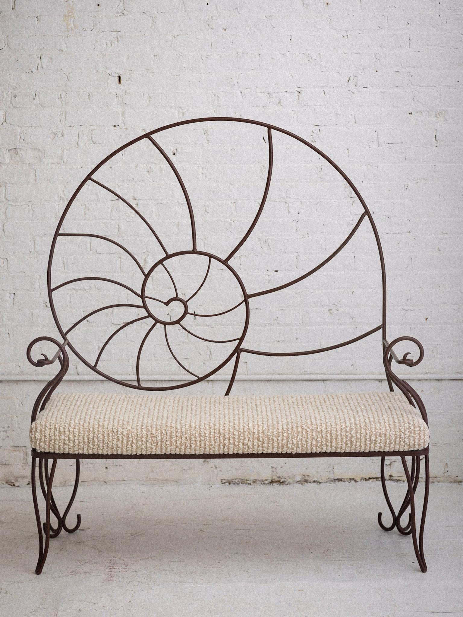 A post modern wrought iron bench. Nautilus form Silhouette. Powder coated in a matte rust color. Newly upholstered cushion in high quality striped wool bouclé.