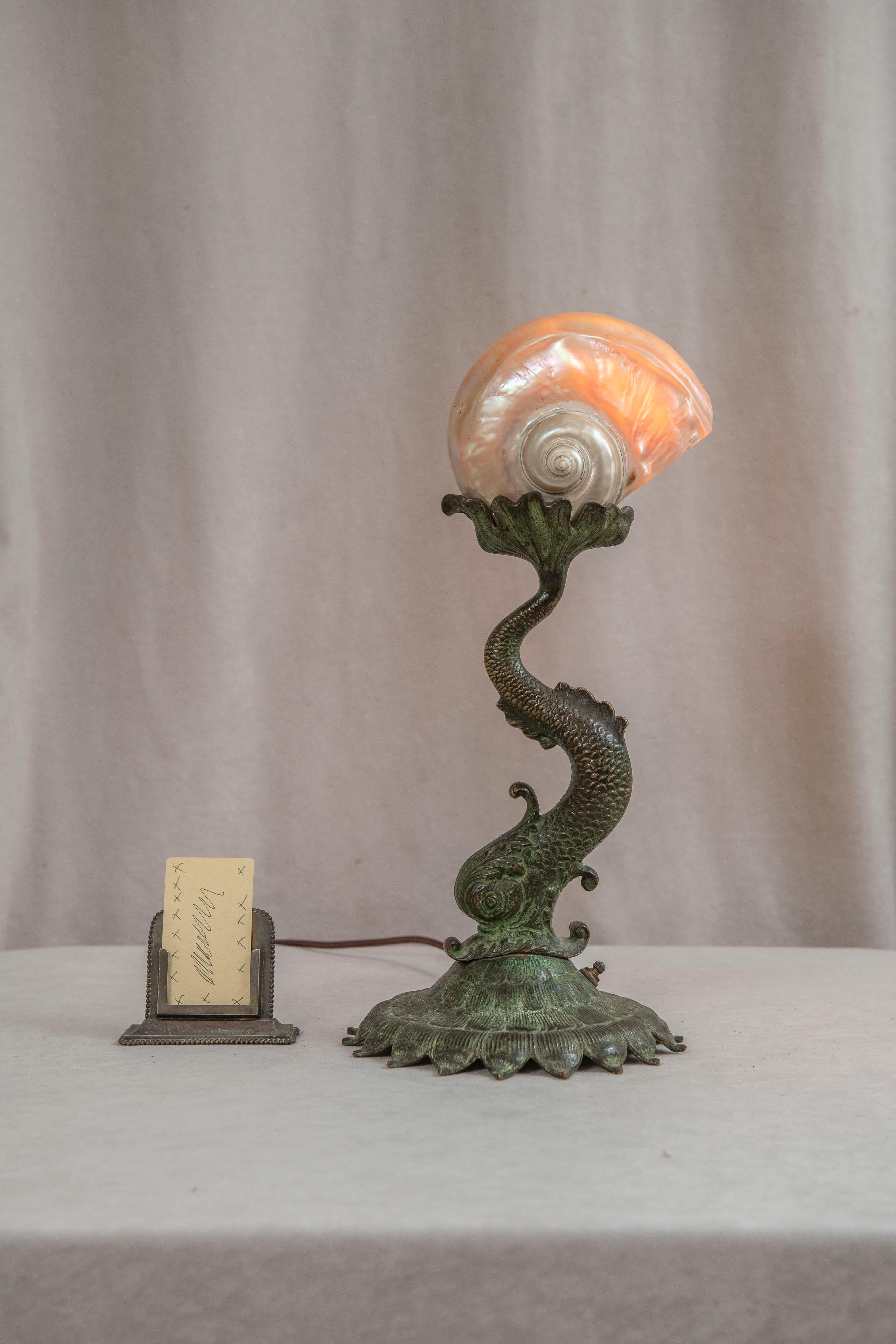  This exceptionally high quality lamp is candy for the eyes. The base is cast bronze with that dolphin like fantasy fish that appears on lamps, furniture and many other objects. The casting is very finely detailed and warmly factory patinated in a
