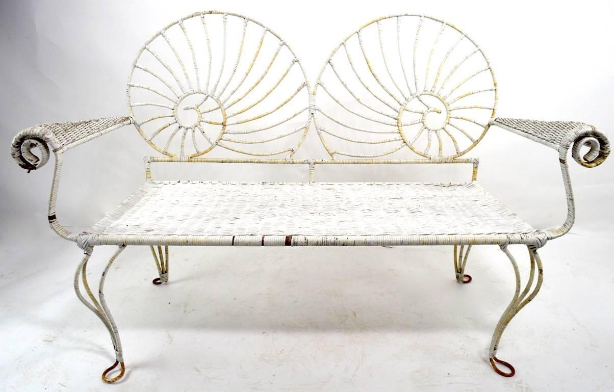 Wicker wrapped Iron loveseat bench with Nautilus Shell motif back. Stylish form, solid and ready to use, wicker shows minor loss, and paint finish shows wear, normal and consistent with age. Please view the matching armchair we have listed, if you