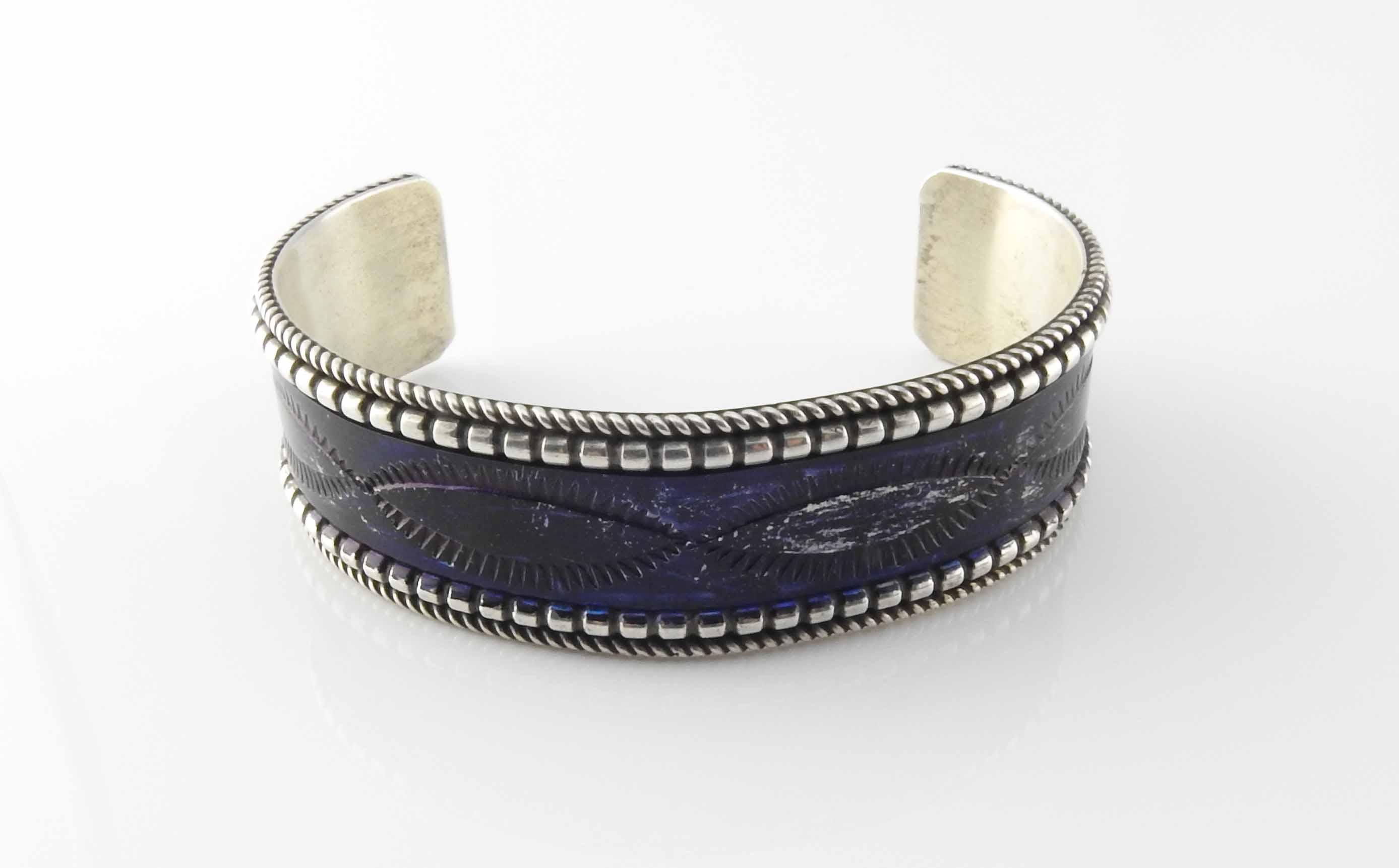 Navajo sterling silver cuff bracelet by Celina Yazzie. Dark purple enamel with embossed design and beaded and roped edges.

Measures 3/4
