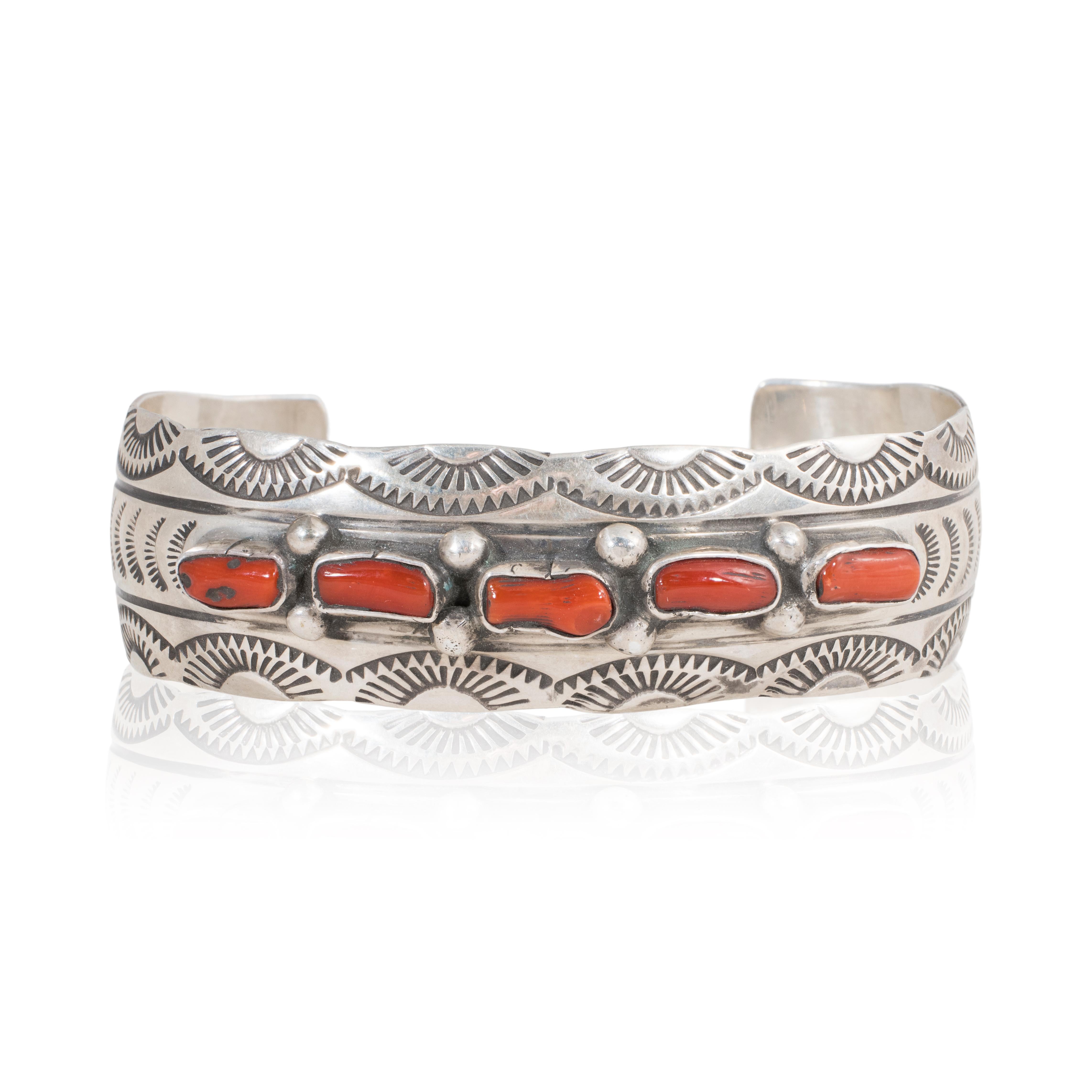 Navajo sterling silver and coral cuff bracelet by J. Lee. This bracelet has five natural coral pieces across the center top portion. The band is completely hand stamped sterling and signed.

PERIOD: Mid 20th Century

ORIGIN: Southwest - Navajo,
