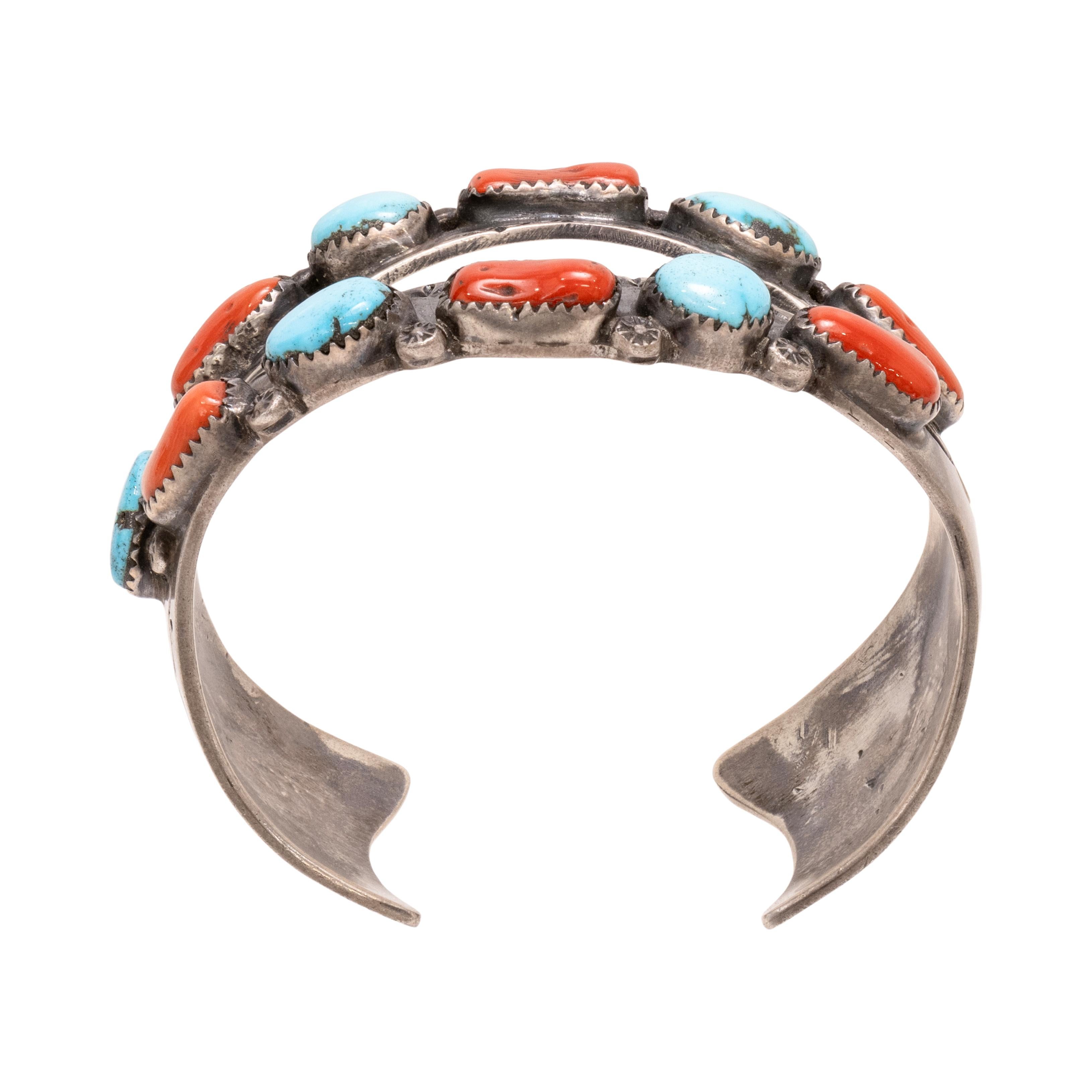 Navajo coral and turquoise bracelet. Signed R.W.J/T.H.M. Double bar bracelet with crystal opening in center. Five turquoise stones and 6 coral nuggets, bracelet having stamped Kokopelli and geometric designs. The turquoise is from the Morenci Mine