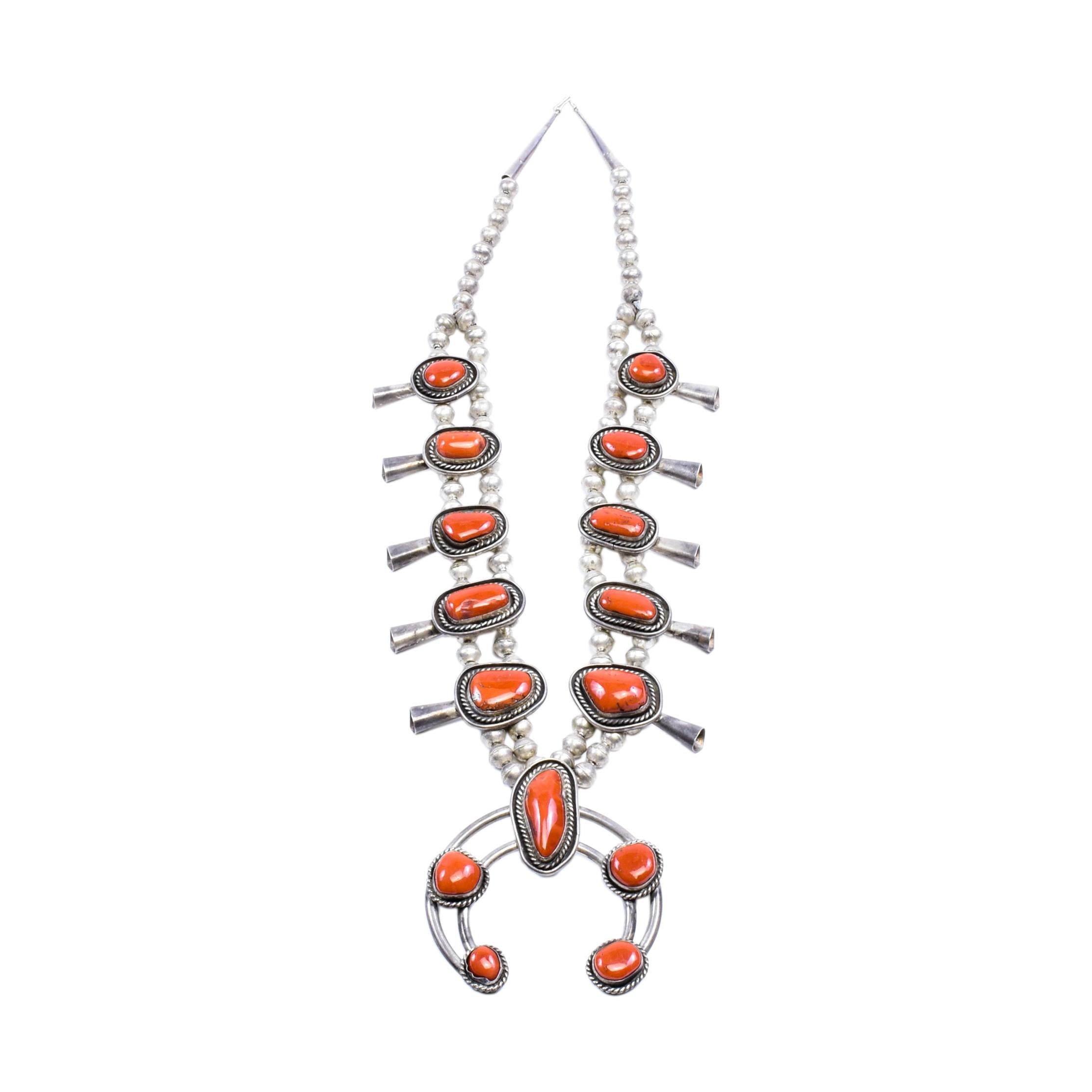 Navajo squash blossom necklace with coral. Set incudes matching earrings. Marked sterling. The Navajo word for the squash blossom bead literally means “bead that spreads out”. This tri-petal form first appeared about 1880. Scholars believe that this