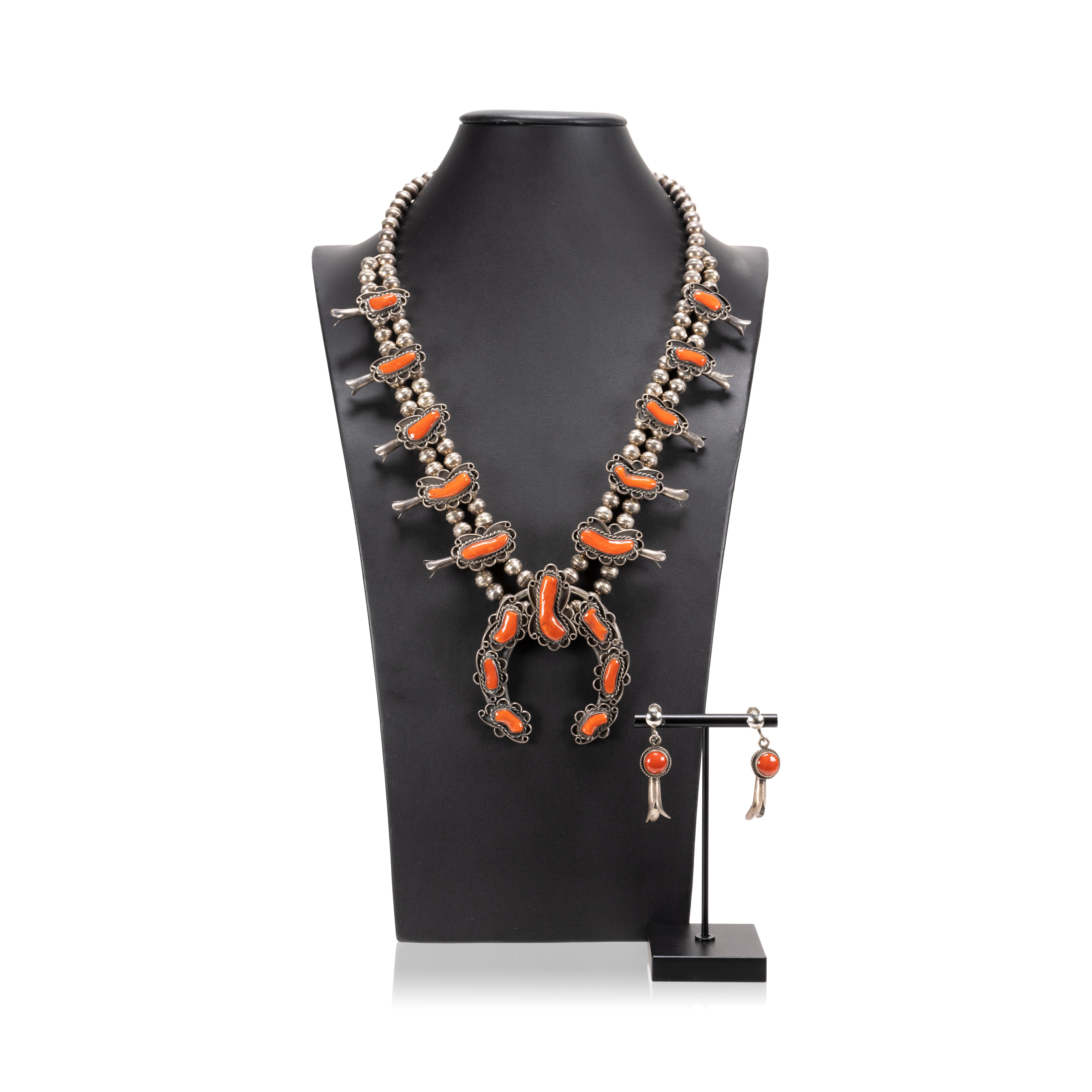 Navajo coral and sterling silver squash blossom necklace featuring a classic naja with seven beautiful coral cabochons accented by twisted rope and light hand stamped designs. The petal blossoms along the neck feature more exceptional, high-grade