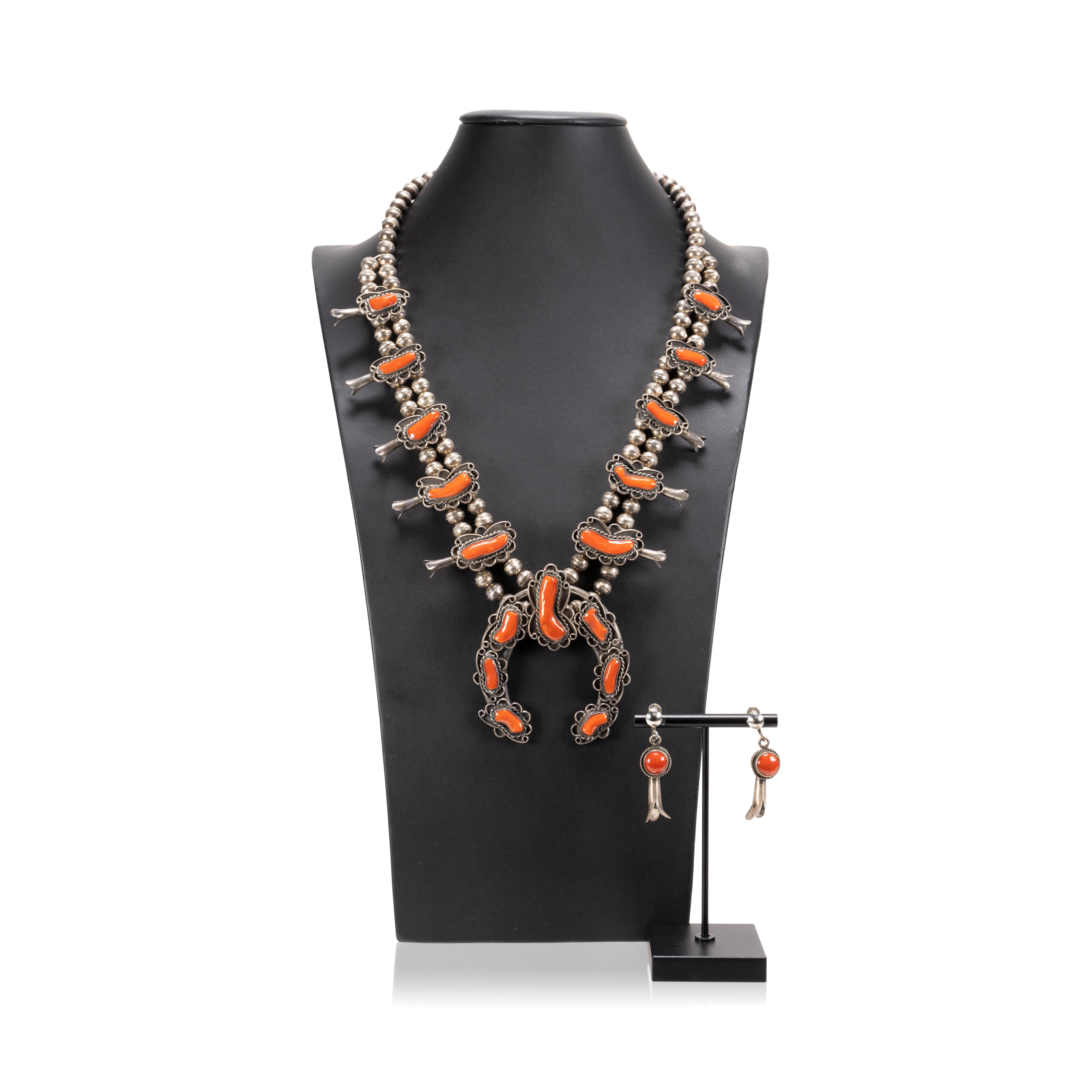 Native American coral and sterling silver squash blossom necklace featuring a classic naja with seven beautiful coral cabochons accented by twisted rope and light hand stamped designs. The petal blossoms along the neck feature more exceptional,