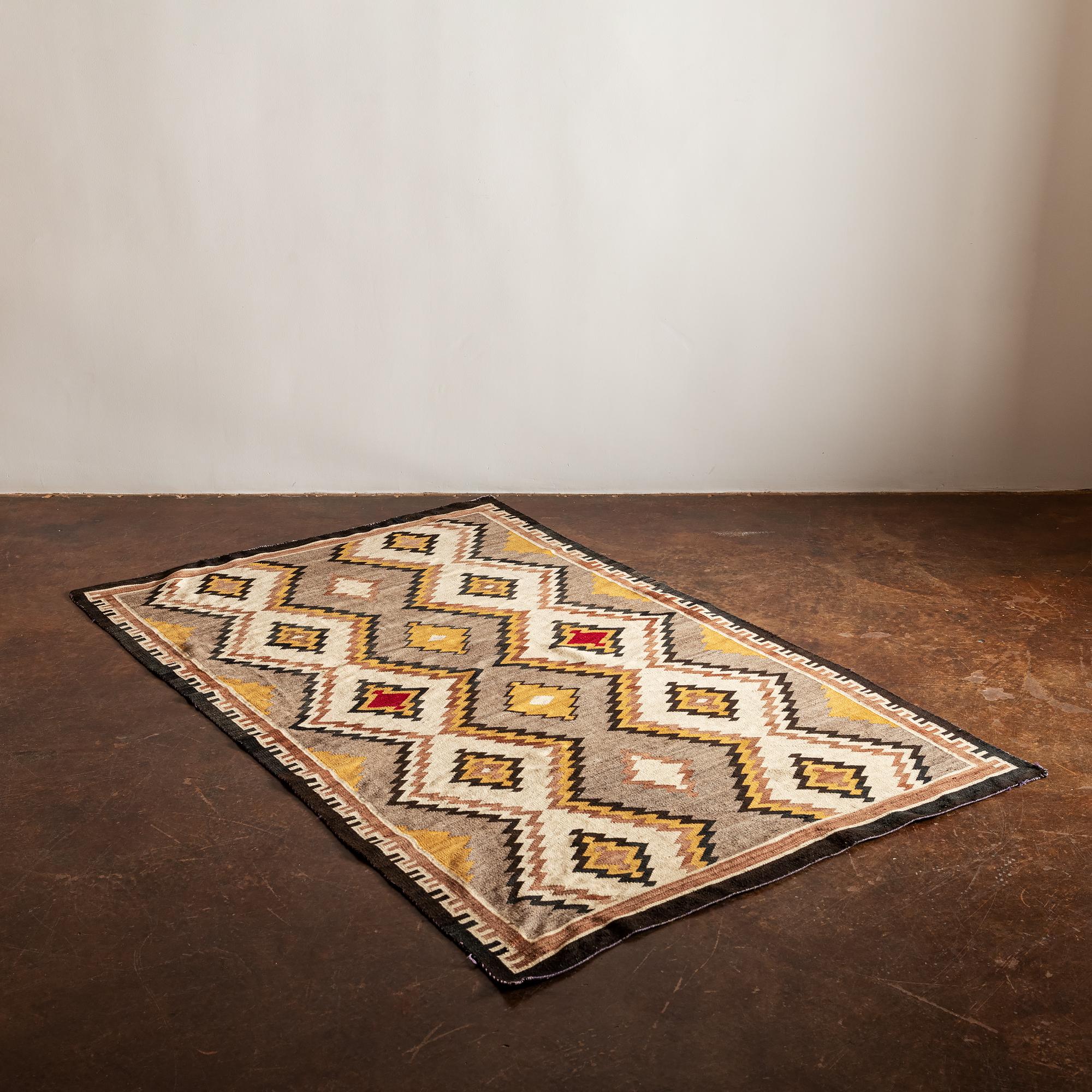 A Classic Navajo eye dazzler textile in ochre, neutrals and a pop of red, 1940s.
