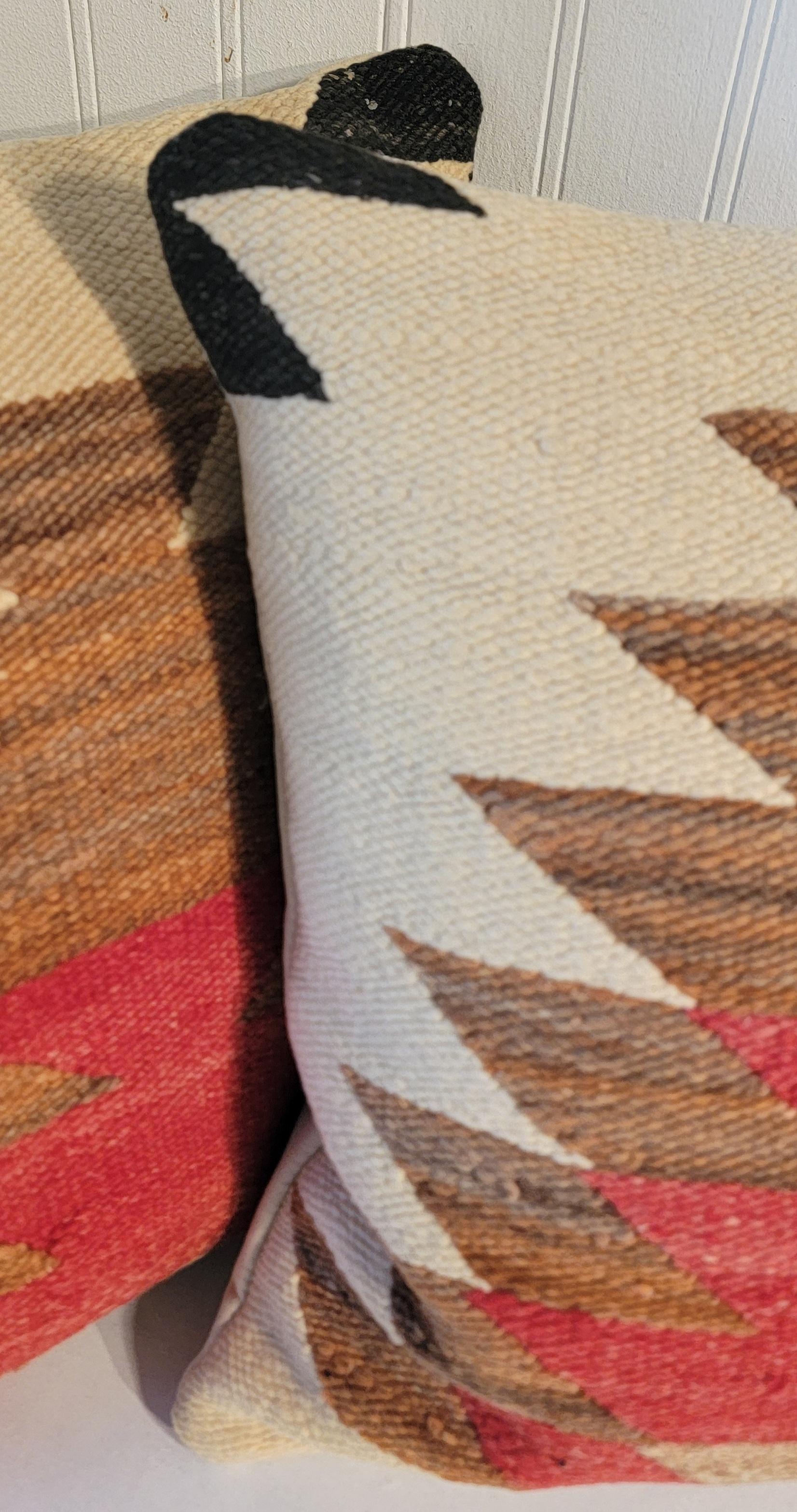 Cette paire de coussins tissés par les indiens Navajo sont dans des couleurs sourdes et ont des dos en lin. Les inserts sont en duvet et plumes. Vendu par paire.