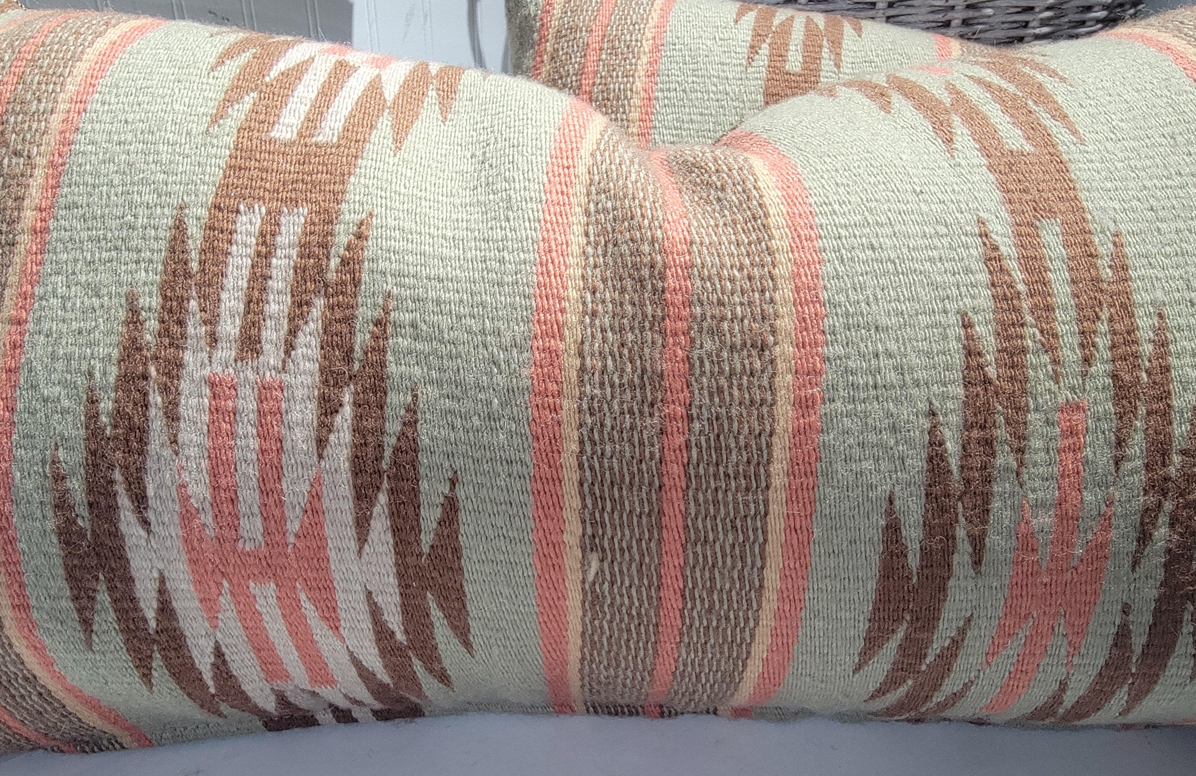 Salmon & khaki green Navajo Indian weaving bolster pillows.The backings are in a thick sage green linen.Down & feather fill. Sold as a pair.