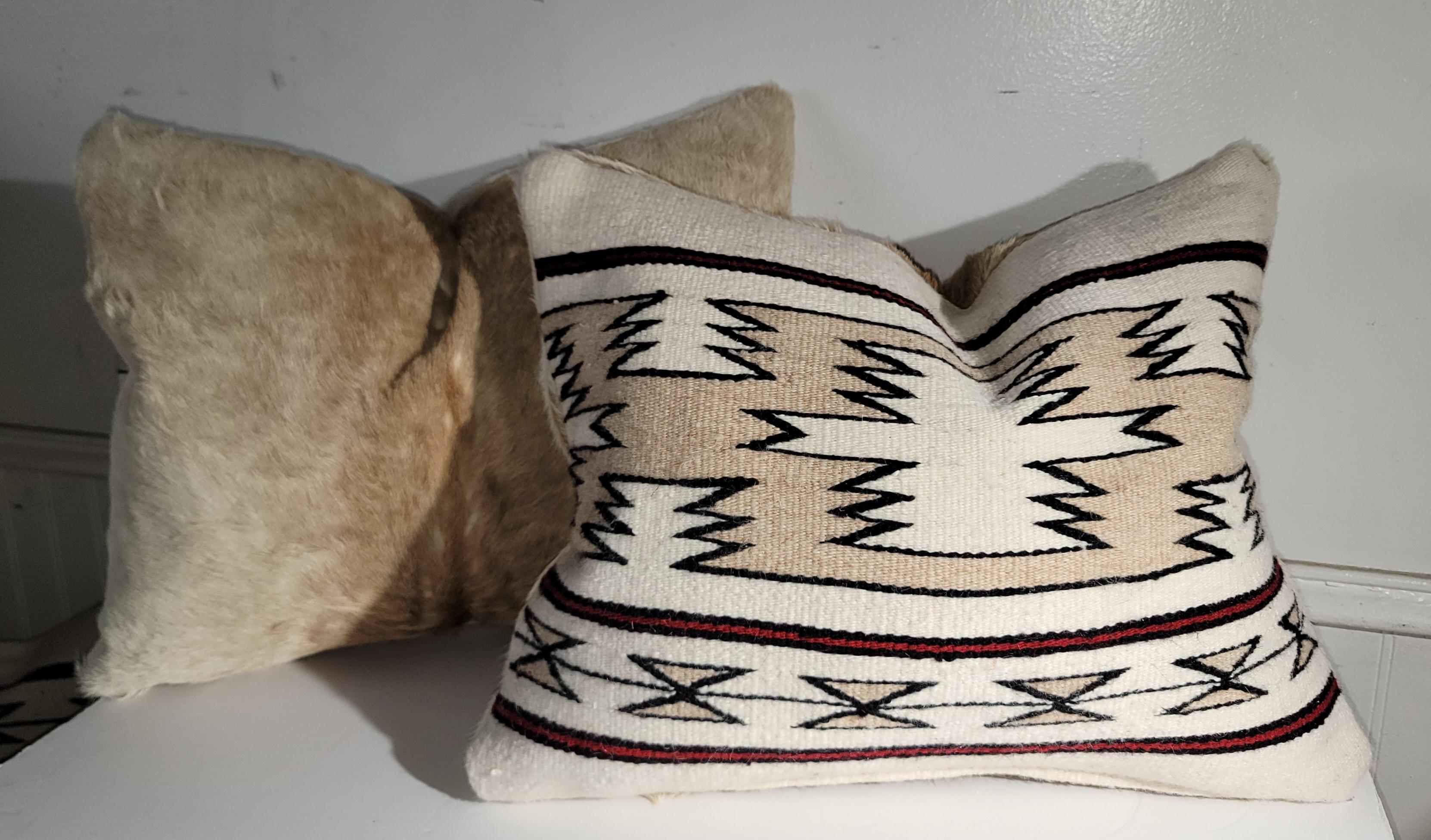 Cette paire de coussins géométriques en tissage indien Navajo a un dos en peau de veau dans des couleurs douces.