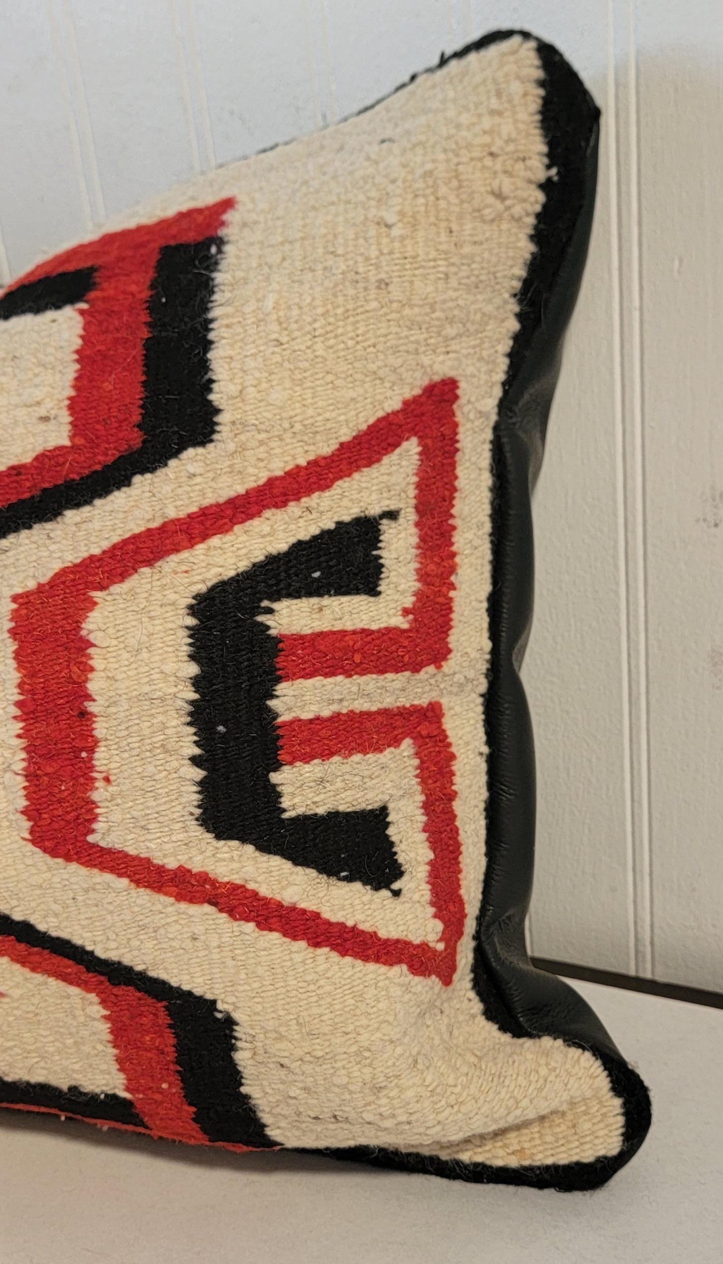 Les premiers Indiens Navajo  Oreiller en tissu géométrique avec un support en cuir noir, garni de duvet et de plumes.