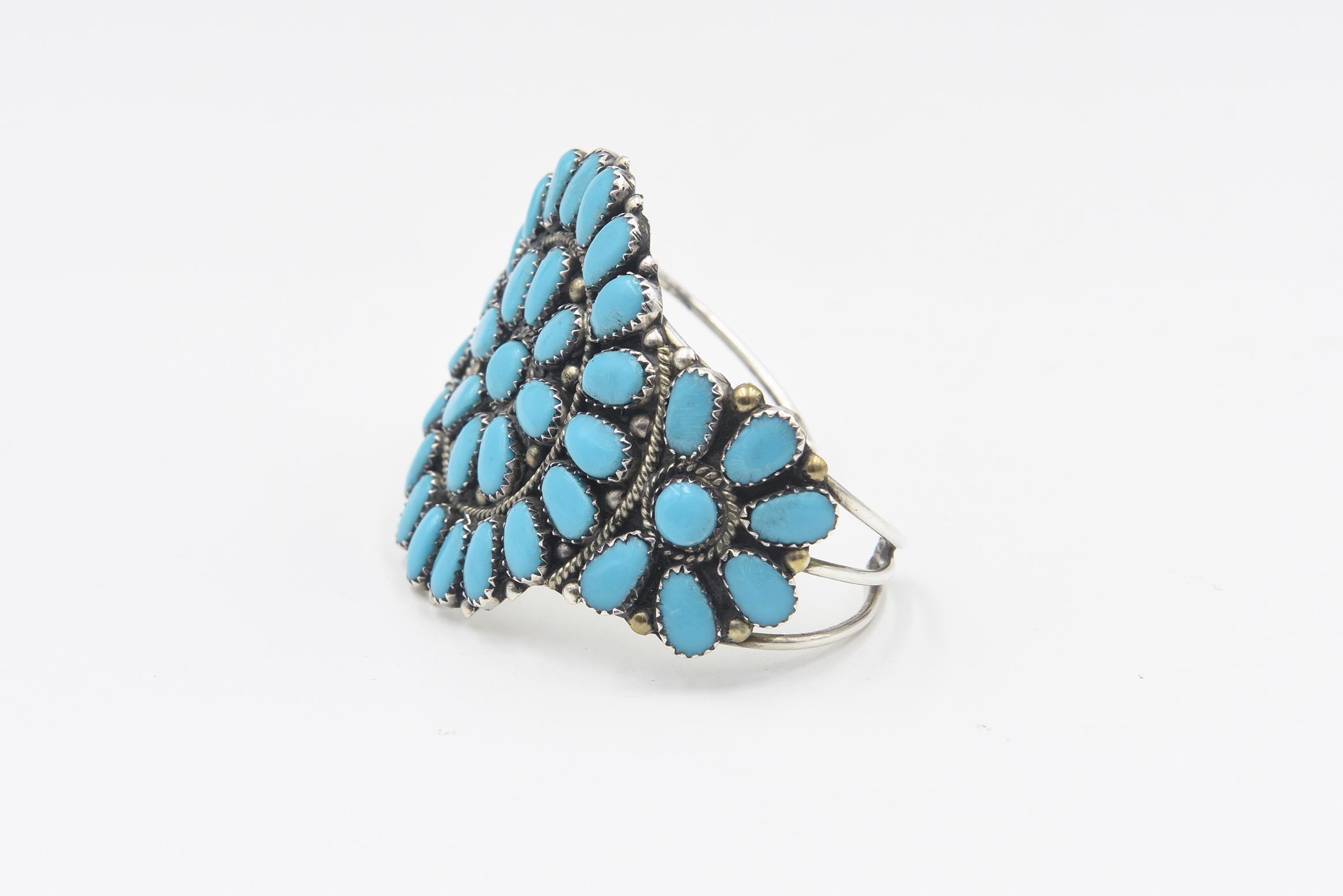 Beautiful vintage sun wheel cuff bracelet by Navajo Native American artist Juliana Williams made of sterling silver and turquoise.  The artist uses a clusters of turquoise pieces to create a sun in the center and a smaller suns on either side. 
