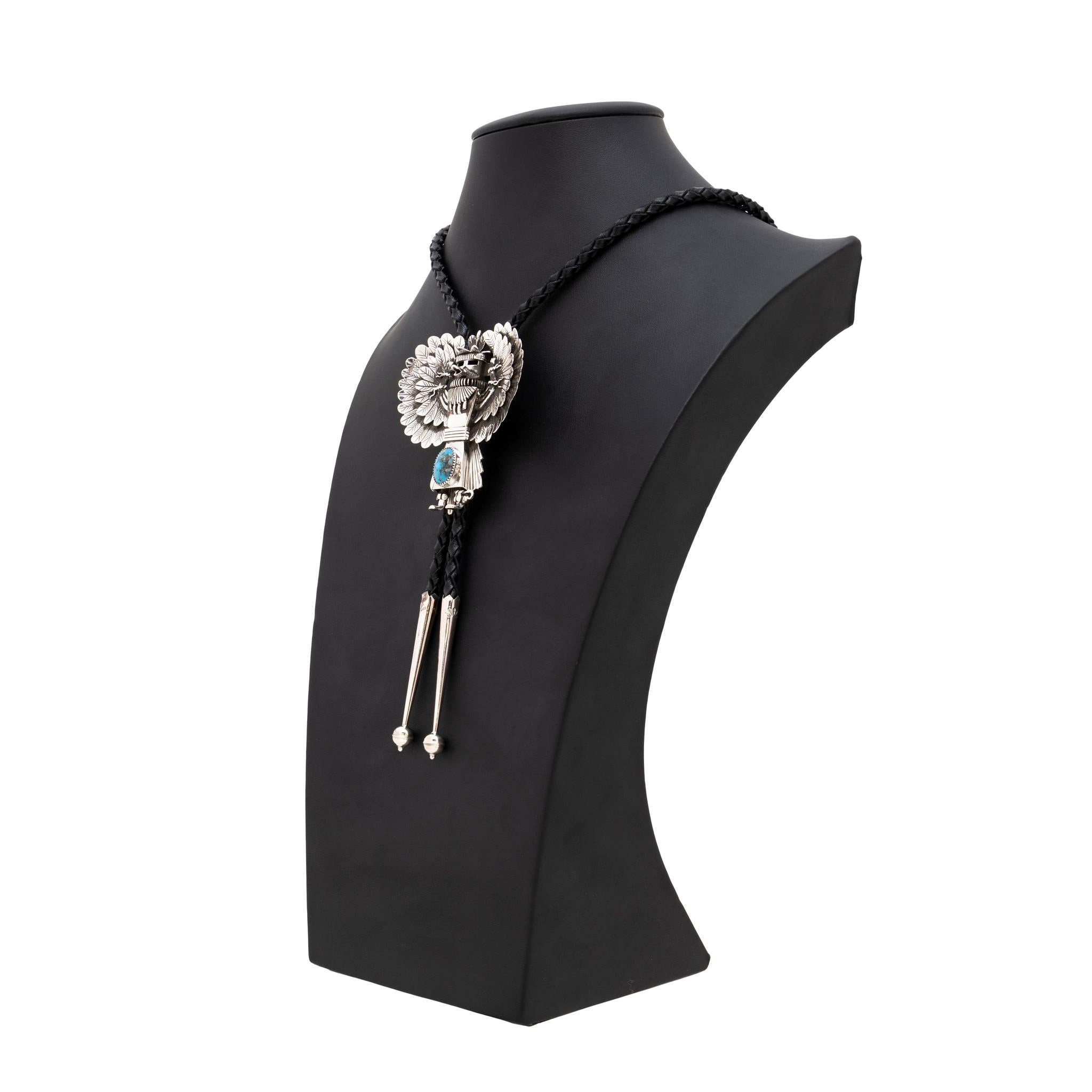 Bolo in argento sterling dell'argentiere indiano Navajo Avin Joe a forma di Kachina dettagliato con una singola pietra di turchese Kingman su una cravatta di corda nera intrecciata. Timbro in sterling e marchio del produttore. Un pezzo di grande