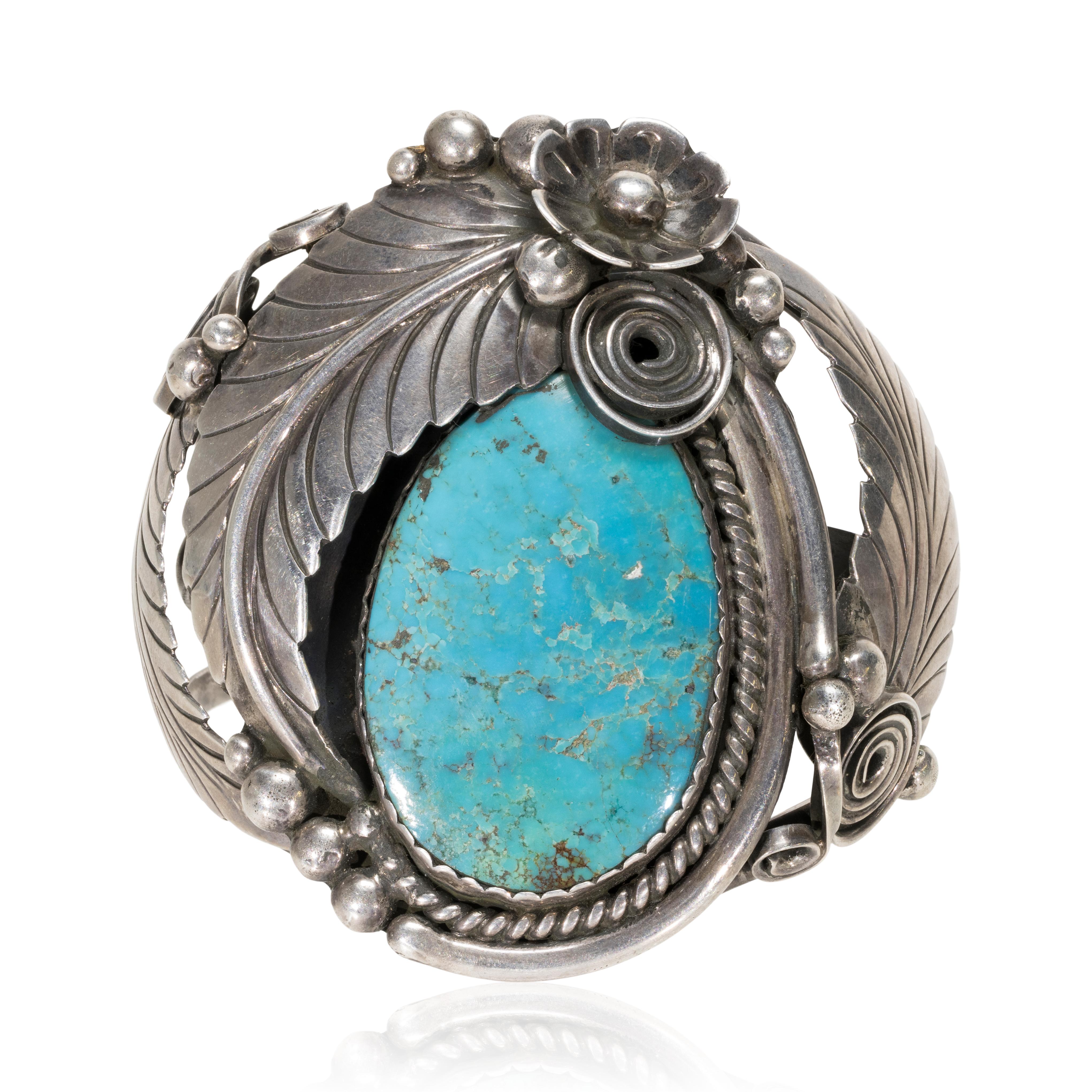 Navajo Kingman turquoise and sterling racelet. Beautiful large stone surrounded by twisted rop leaves, flowers and scrolls. Some flexibility to the wrist. Nice patina that can be buffed out easily to make shine.

PERIOD: Late 20th Century

ORIGIN: