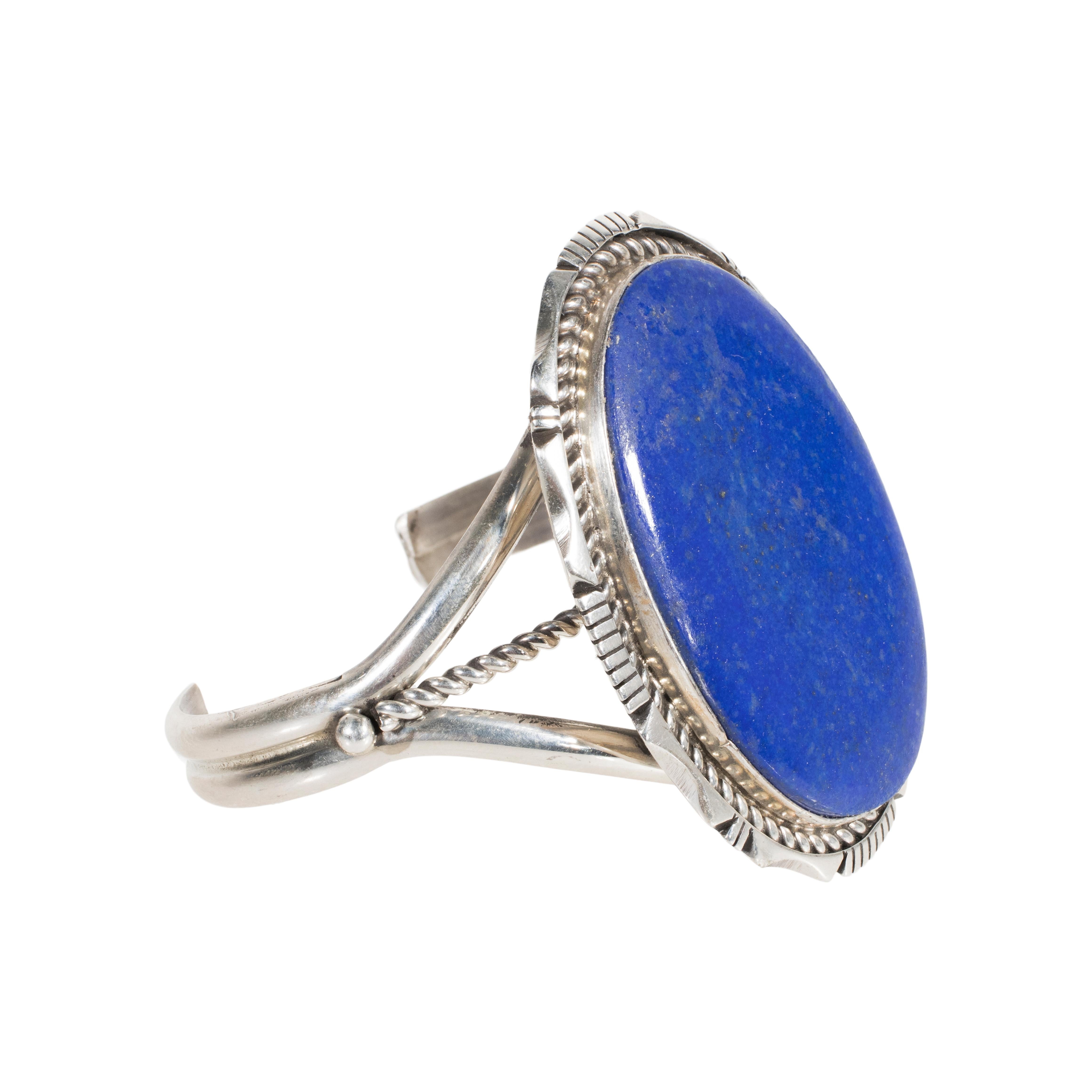 Sterling silver lapis cuff bracelet by Eddie Sacattro. This bracelet has a large oval cut lapis center stone accented with a rope and notched frame. Stamped sterling and hallmarked ES.

PERIOD: Mid 20th Century

ORIGIN: Southwest, United