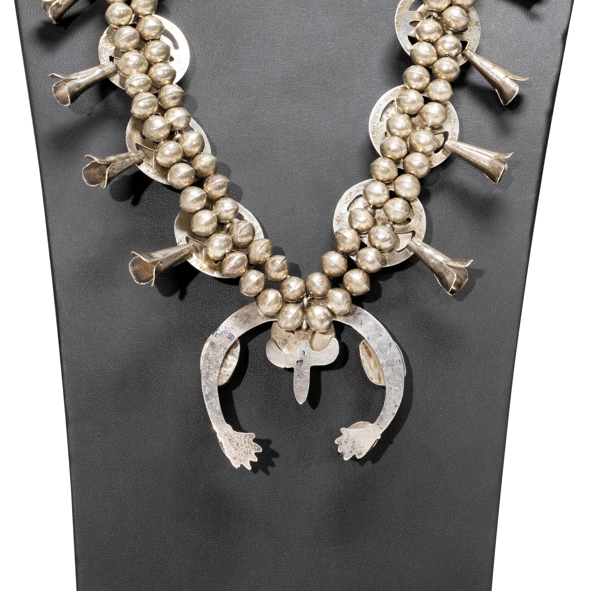 Navajo Morenci turquoise and sand cast sterling squash blossom necklace. Each sand cast petal with 10 raised natural stones ending in a matching additional 5 stone sand cast naja. Each stone surrounded by flilgree star design set in circle. Stones