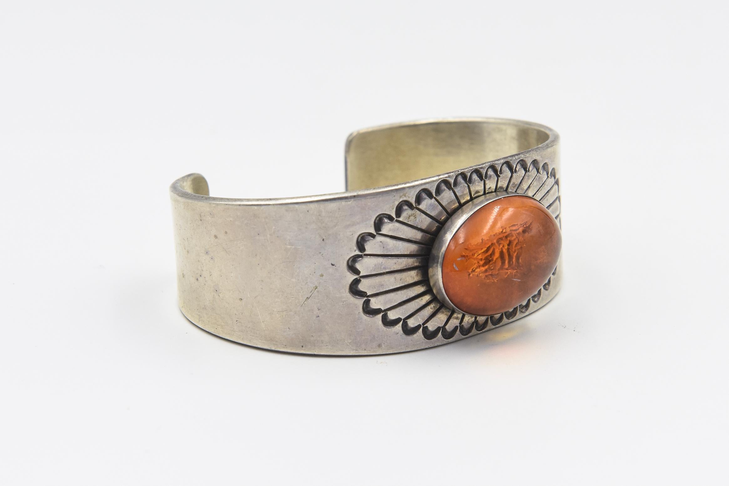This is a beautiful Native American Navajo amber and sterling silver sunburst flower cuff bracelet was made by . The silversmith overlays an amber setting to the smooth silver cuff. It's set into a smooth silver bezel and mounted onto a sunburst