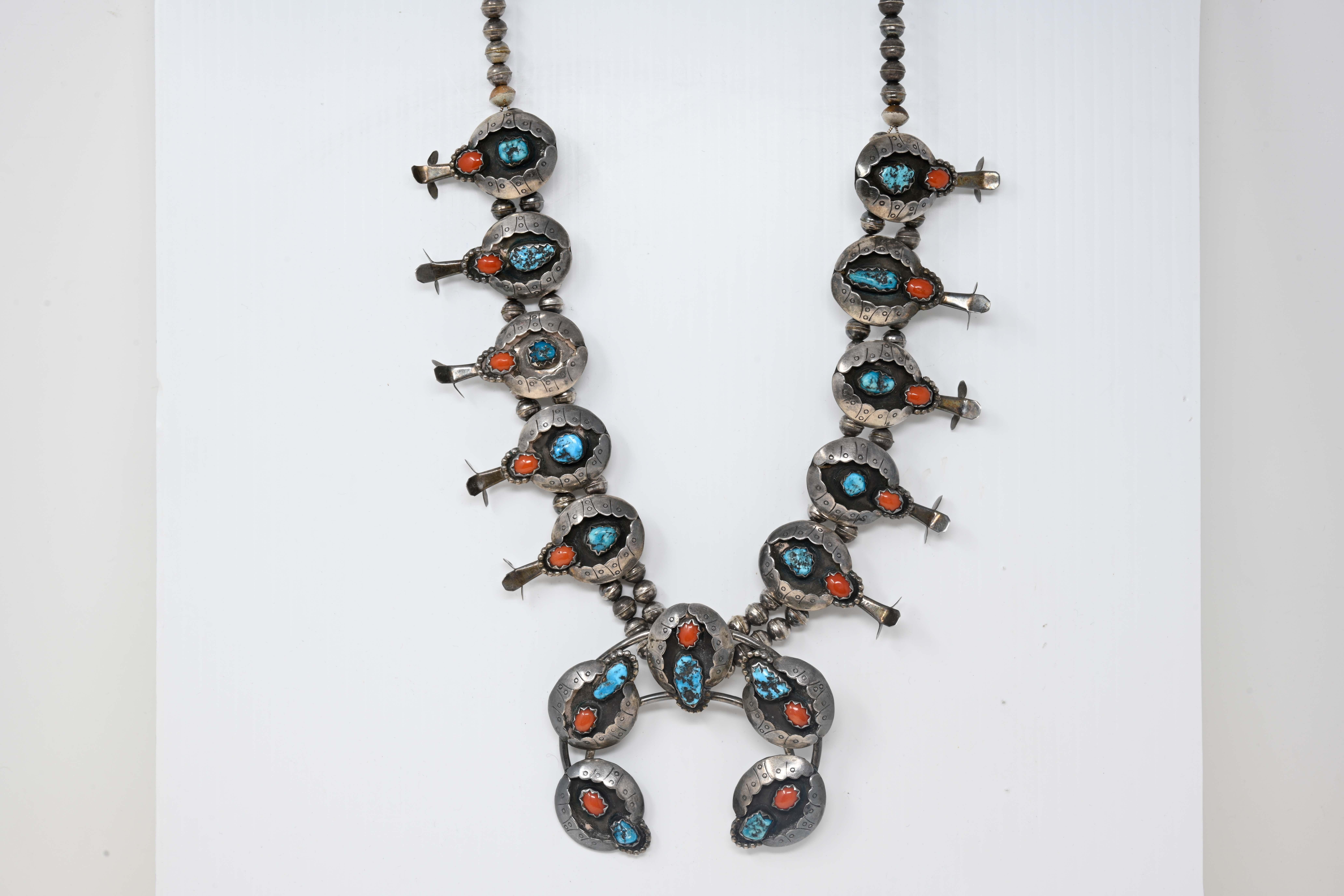Native American Navajo squash blossom sterling silver turquoise coral necklace. Signed on the back Elizabeth M. Thompson, no silver mark but acid tested. The necklace is made of chunks of turquoise and oval shaped coral. The necklace measures 25