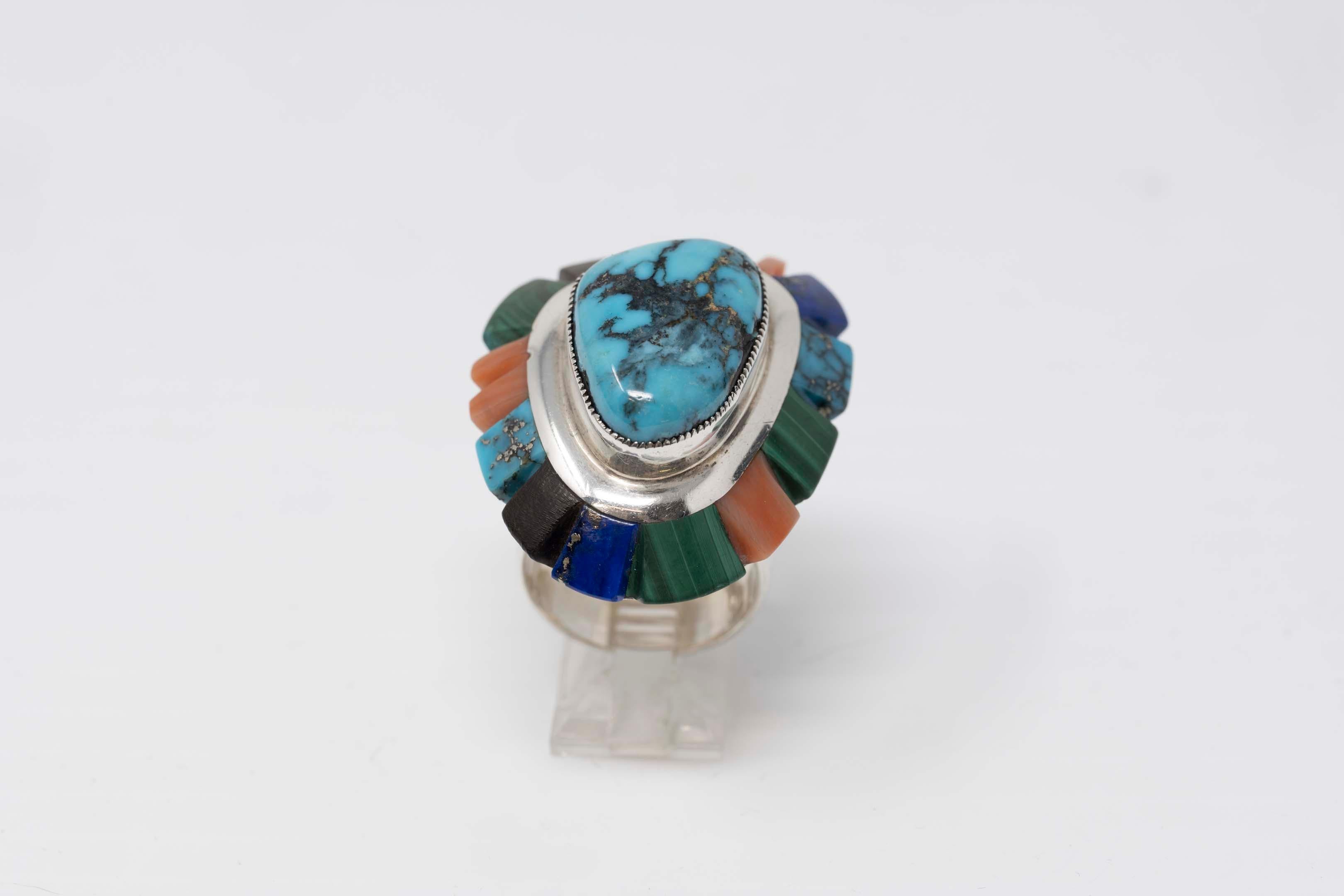 Navajo native American sterling silver with a central turquoise surrounded by multi color stones including lapis, malachite, onyx, turquoise each. Size 8, signed inside. Signed Saunsa. The ring measures at the top measures 37mm x 30mm, the central