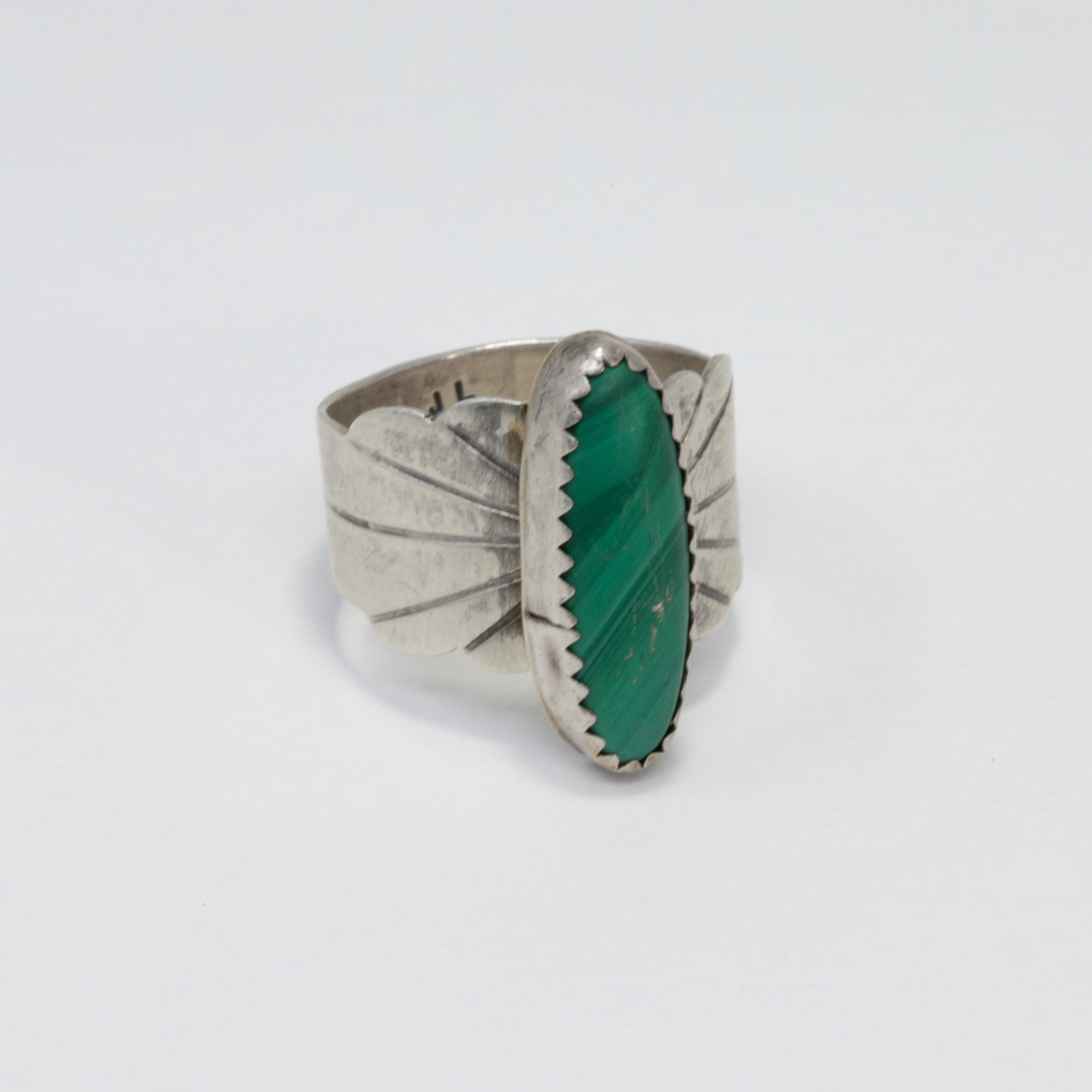 An exquisite vintage cocktail ring! This Native American accessory features an accented sterling silver band with a malachite cabochon. Navajo design and make.

Size: US 7

Marks / hallmarks / etc: JL Sterling