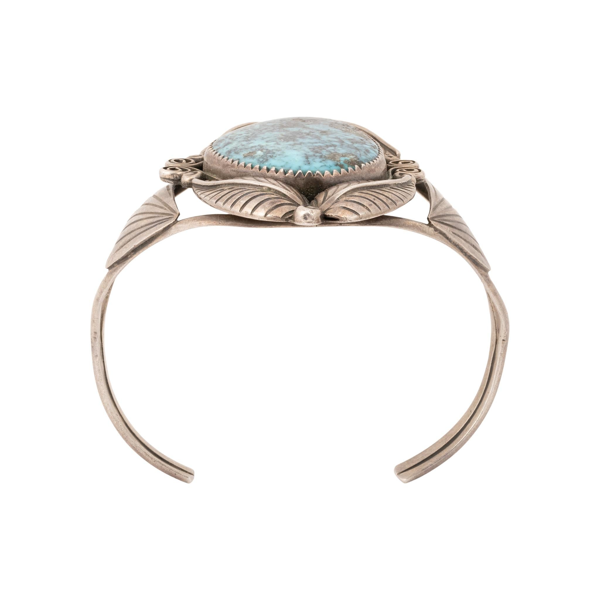 Navajo rare Red Mountain turquoise and sterling silver cuff bracelet. Single-stone in sawtooth bezel setting, surrounded by silver scrolls and feathers. Stone is a deep blue with exceptional dark and gold matrix, attached to double band cuff. Framed