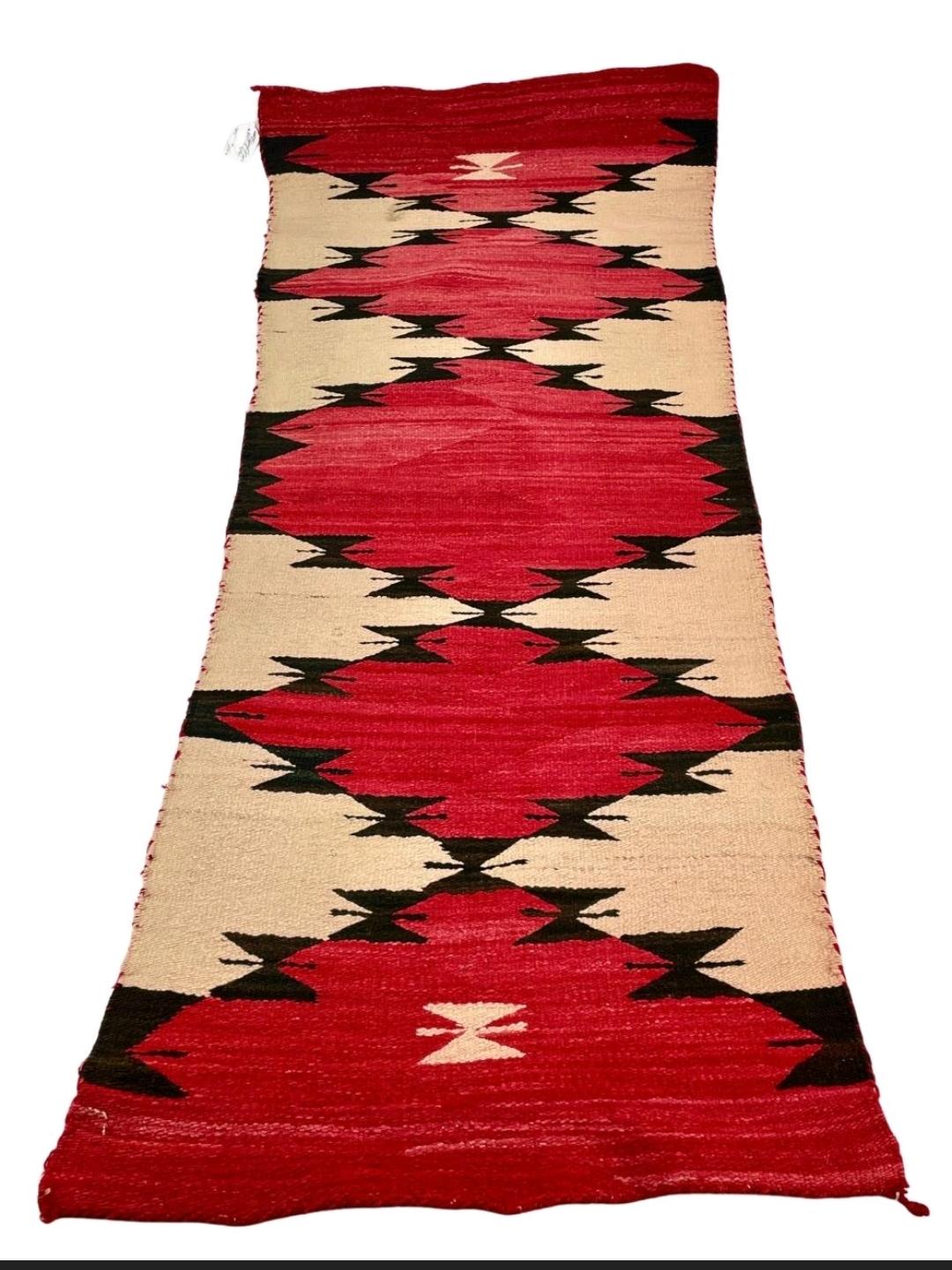 Purchased circa 1900 from a trading post in Chaco Canyon, New Mexico. A hand woven Navajo runner with red, black and cream coloring of very dramatic design. 
From the lifelong collection of Edythe and Donald Aukerman.
