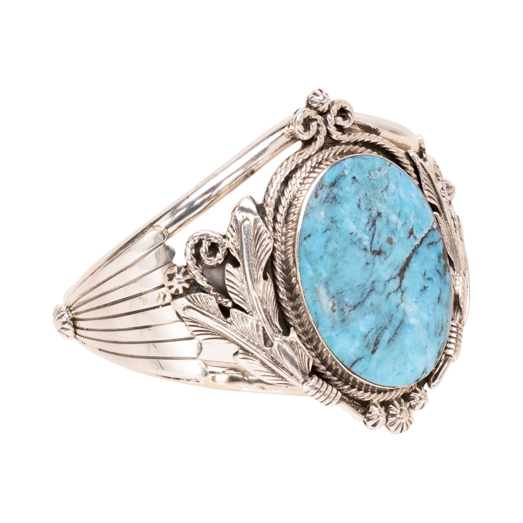 Bracciale Navajo in argento e turchese. Con una singola pietra Kingman incastonata in un bracciale decorativo con piume, bordo in corda intrecciata, perline in sterling stampate e accenti a ventaglio sui lati. La pietra è di colore azzurro con
