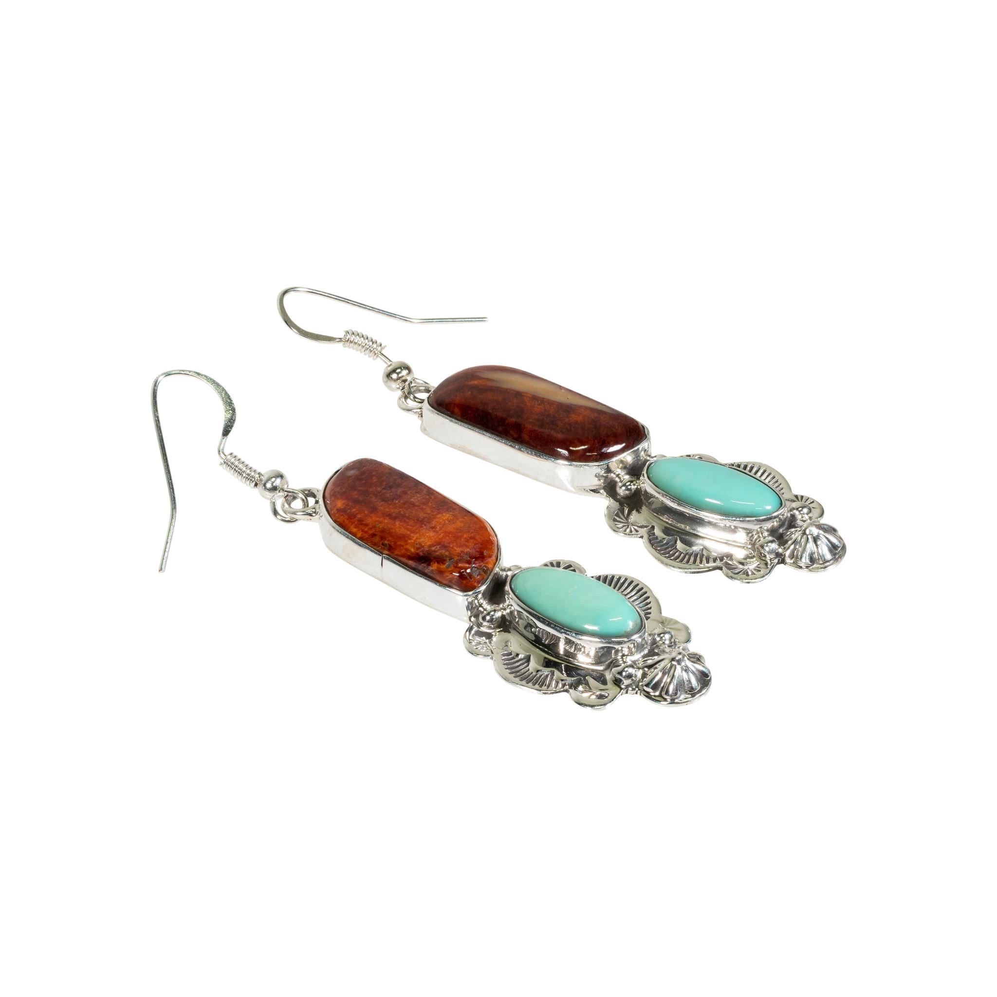 Navajo dangle earrings with purple spiny oyster stone at the top and a natural turquoise oblong stone at bottom. The turquoise is accented with a hand stamped frame. Marked “Sterling” and hallmarked “L”.

Period: After 1950
Dimensions: 12.6 grams,