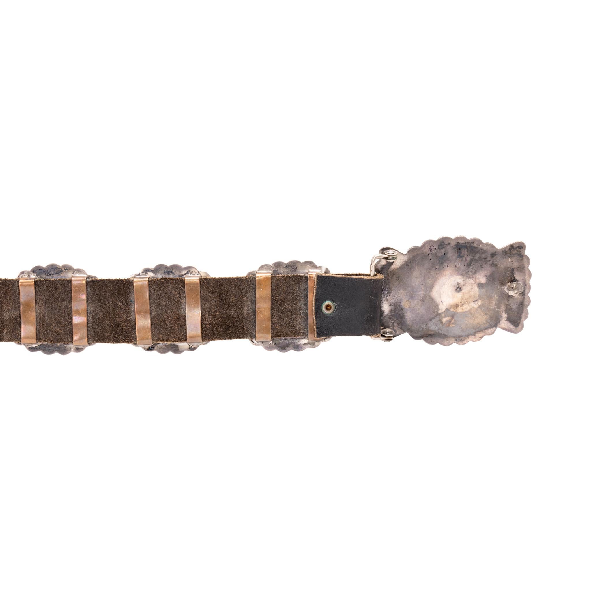 Navajo sterling silver and turquoise concho belt. Twelve oval shaped three-dimensional conchos with matching buckle having fan designs on either side. Each concho having single oval cut Kingman turquoise stone in sawtooth bezel setting. Sterling