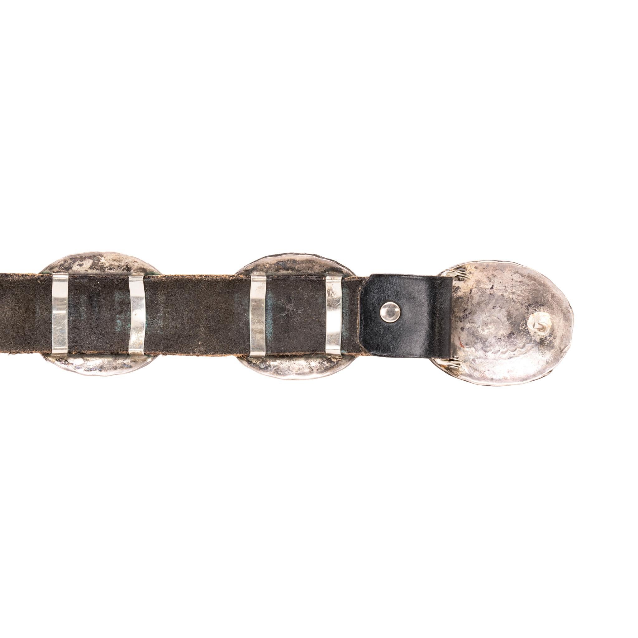 Navajo sterling silver concho belt. Nine oval conchos with matching belt buckle. Each concho hand stamped with traditional designs and smooth borders. With double sterling loops attaching them to dark brown leather belt. Nice patina to silver that