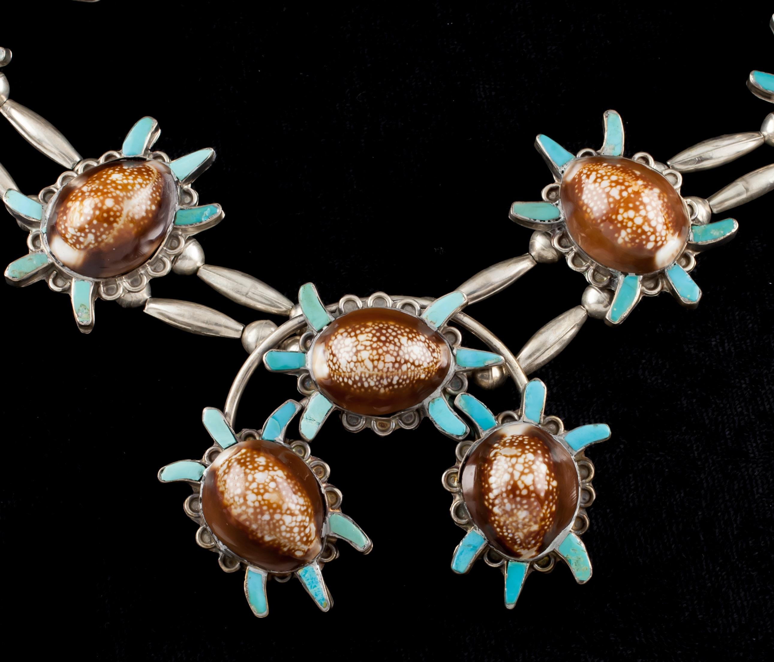 Sterling Silver Native American Squash Naja Necklace 
Accented with 8 brown shells qurrounded by turquoise pieces and squash blossoms (excluding centerpiece)
Sterling silver bead double strand necklace
Center piece measures approximately: 2.5