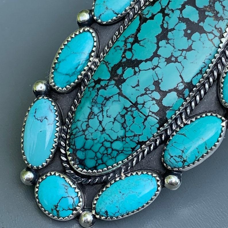 L'anello da cocktail vintage è una testimonianza dell'arte dell'argenteria Navajo. Realizzato con cura, presenta un sorprendente gruppo di pietre turchesi autentiche incastonate in una base in argento sterling fatta a mano.

Materiali:
Argento: