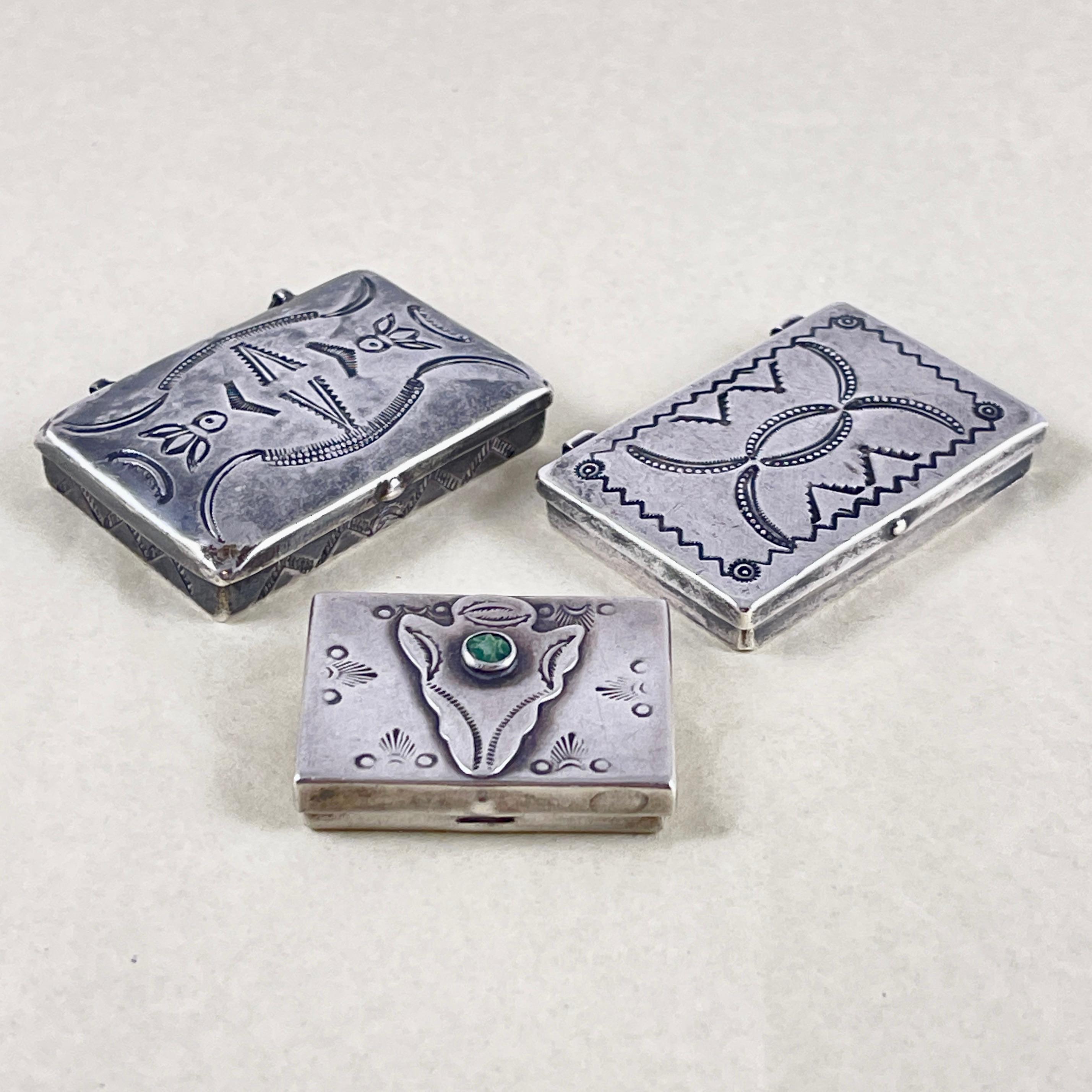 A set of three hand made sterling silver pill cases or trinket boxes, Navajo, Native American – circa 1930s.

The boxes are decorated with tribal stamp work.

1. Box with a convex lid, stamp work to the top and sides. 1.75 in. L x 1.13 in. W x
