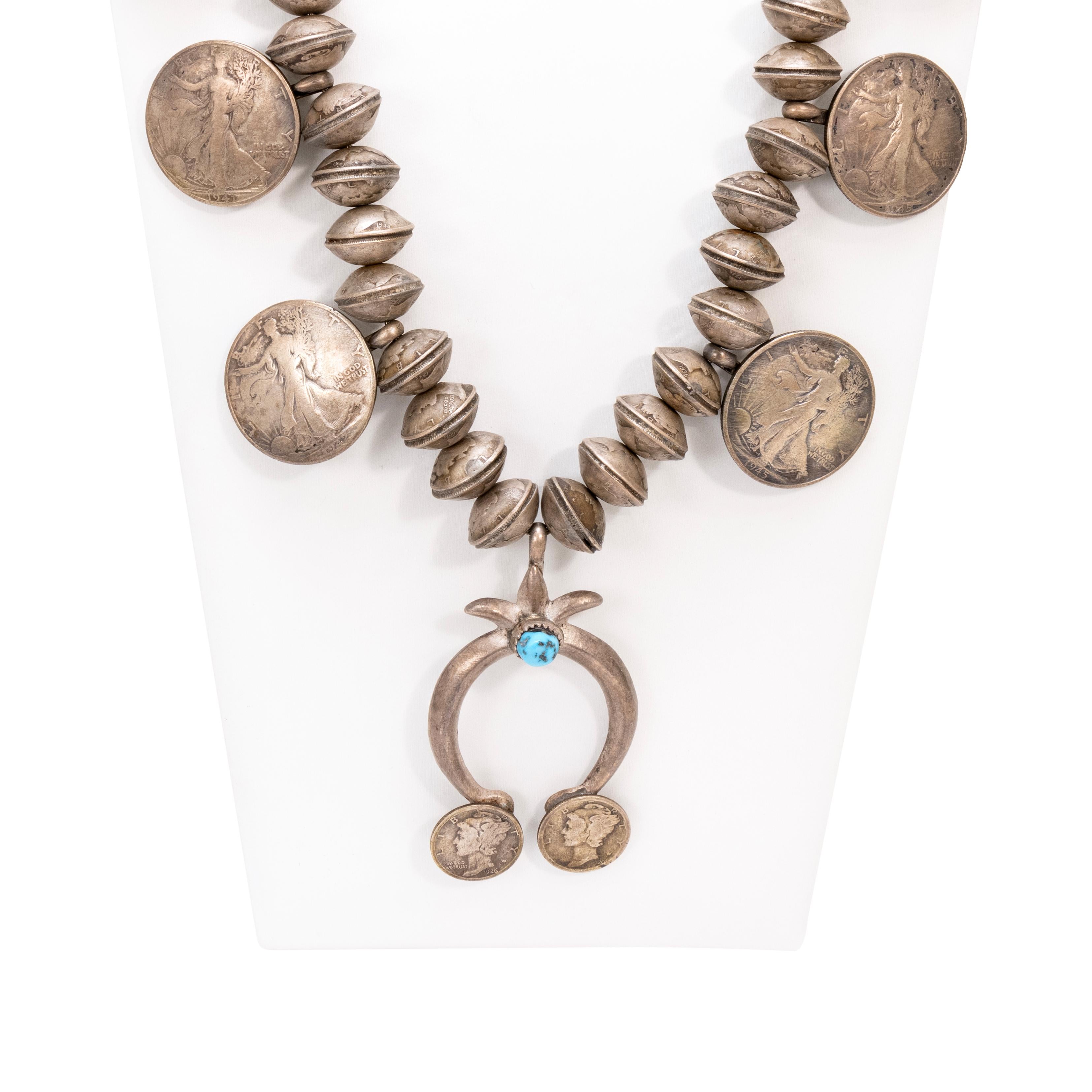 Navajo sterling silver and squash blossom. Each bead is a coin hand stamped together. Center Kingman turquoise stone in naja. Four Liberty 1945 coins and two smaller ones on naja. Old Pawn. Acquired from a Navajo trader.

The Navajo word for the