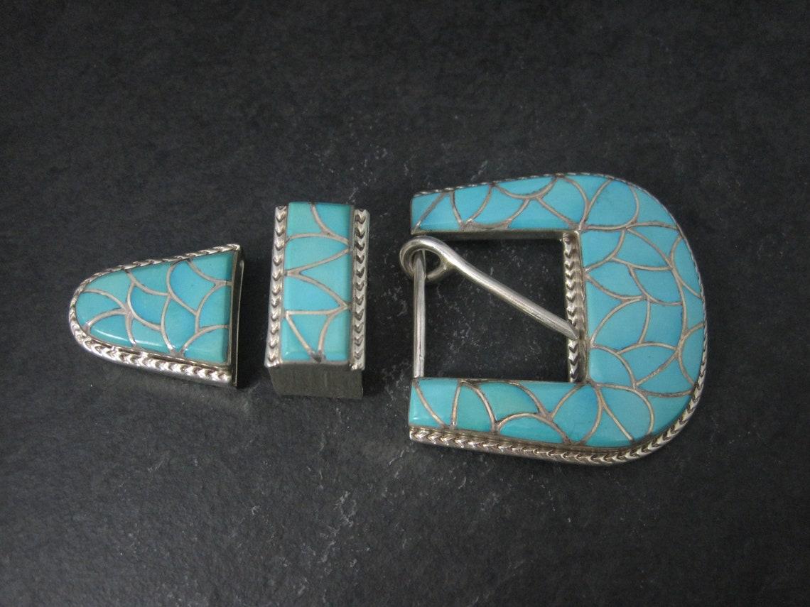 This beautiful belt buckle set is from Navajo silversmith Emma Bonney.
Each piece is sterling silver with turquoise inlay.

The tip measures 1 by 1 1/8 inches - the slide measures 5/8 by 1 1/8 inches - the buckle measures 2 1/16 by 2 1/16