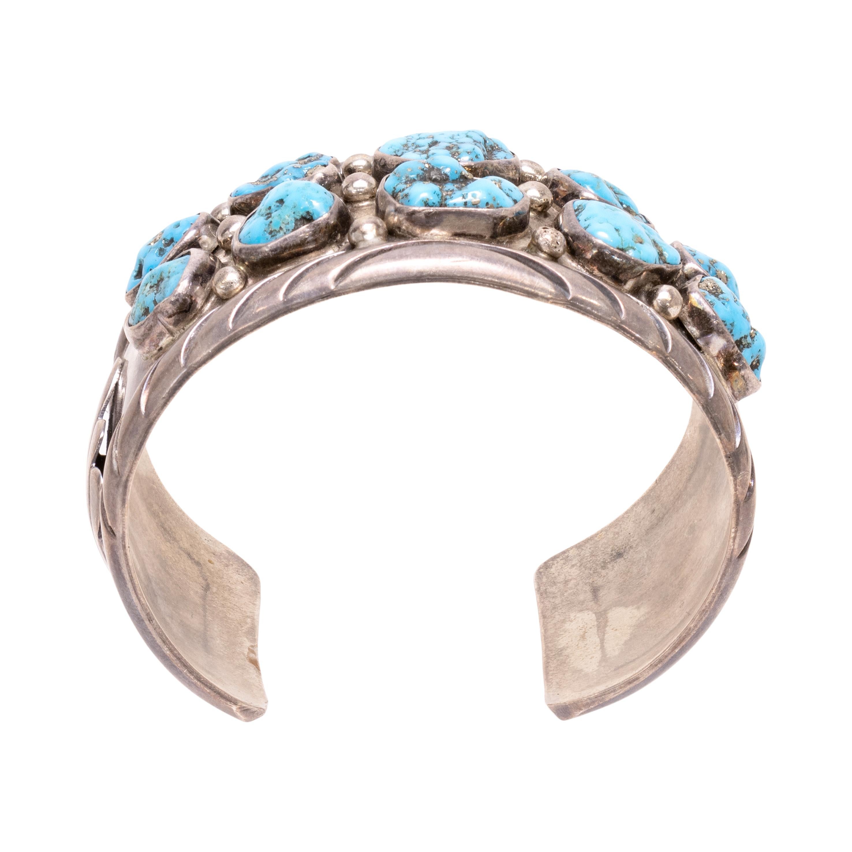Bracciale Navajo con dieci pietre di turchese e argento sterling. Pietre dal taglio asimmetrico incastonate in un castone e fissate a un bracciale in argento massiccio, con perline in argento. Le pietre sono di un blu brillante con matrice scura e