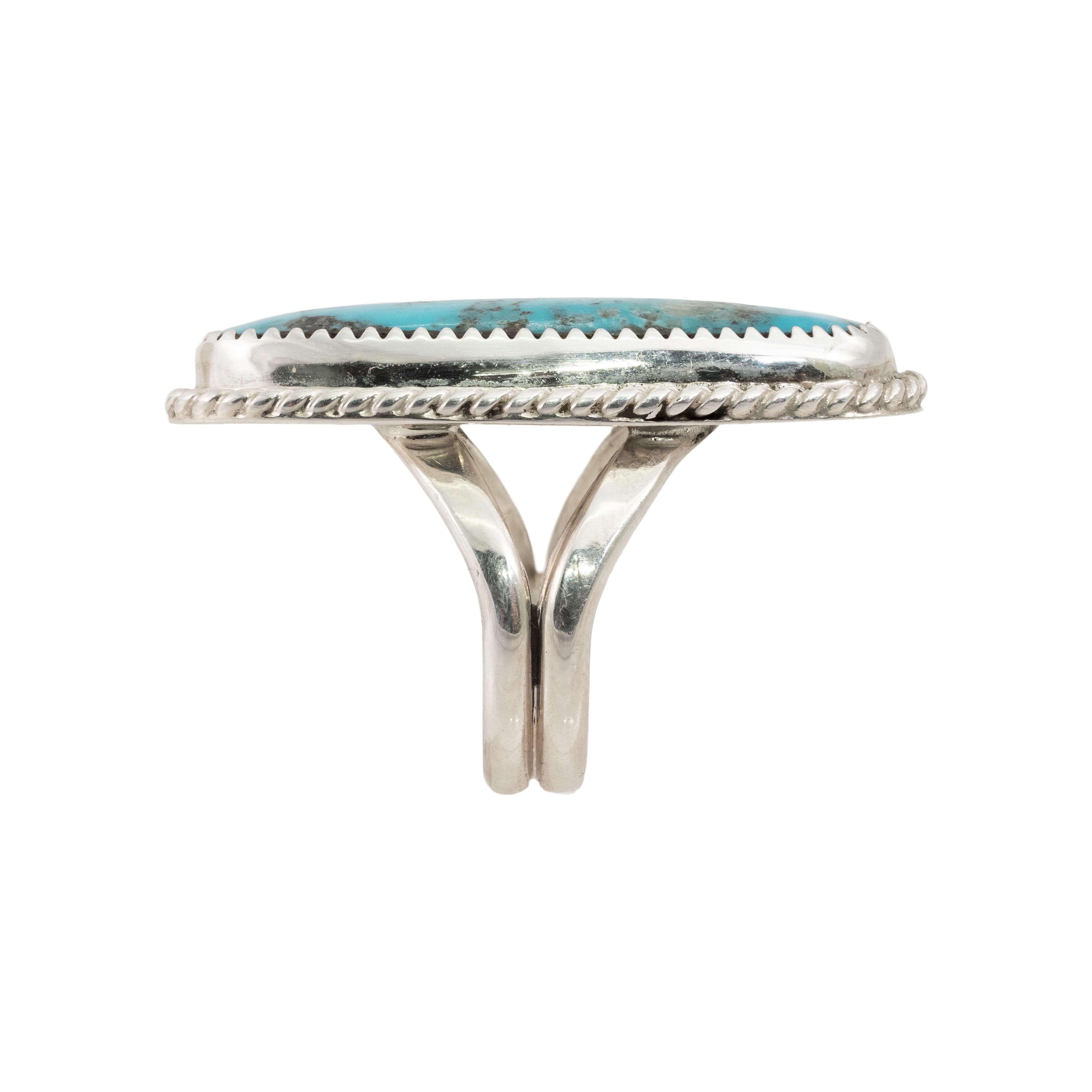 Navajo sterling silver and Triple Creek turquoise ring. The ring displays a sterling silver construction with turquoise set into the center. A large polished nugget of Triple Creek turquoise with a border of silver rope. The back of the piece is