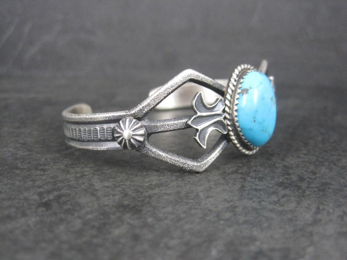 This gorgeous estate cuff is sterling silver with a 14x17mm turquoise gemstone.
It features a tufa cast design.

The face of this cuff bracelet measures 7/8 of an inch wide. It has an inner circumference of 6 1/4 inches including the 1-inch