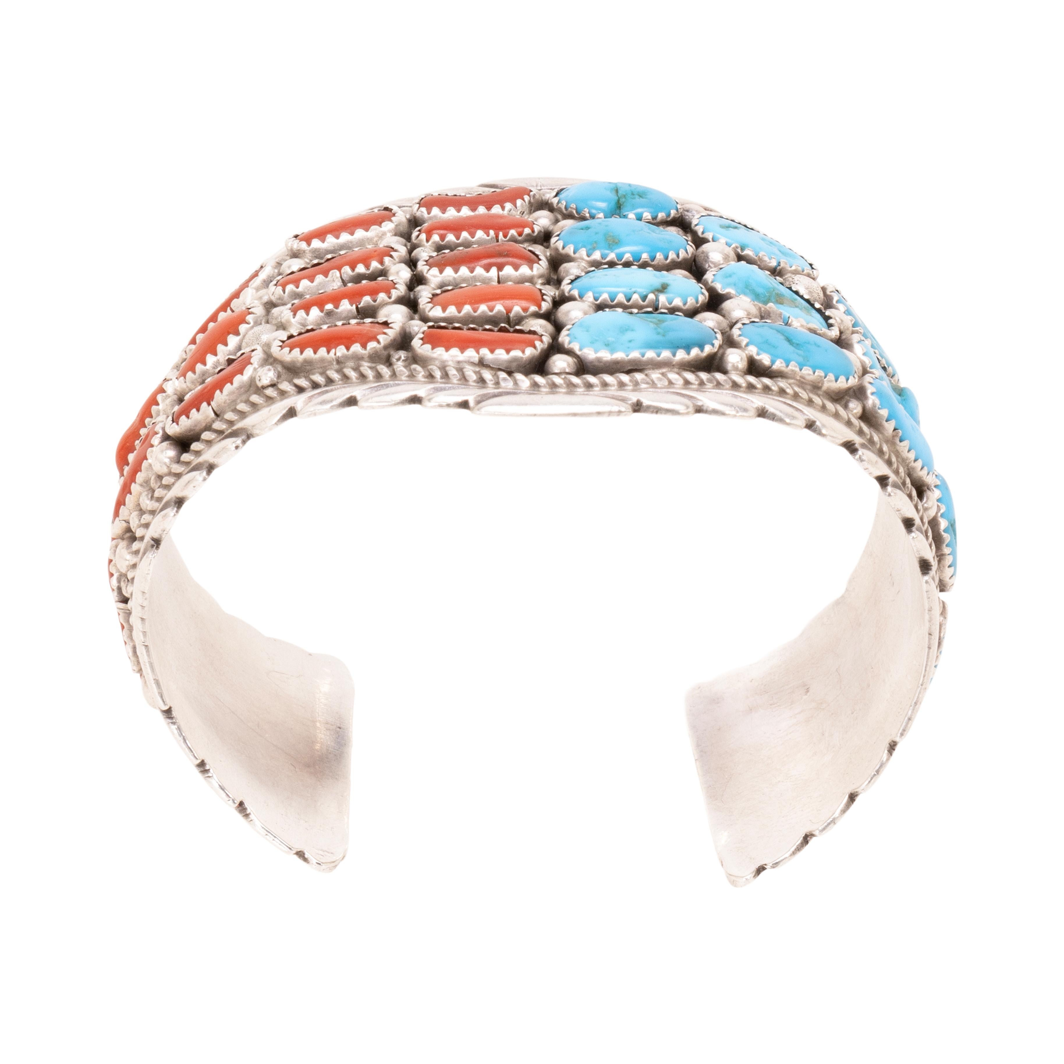Bracelet Navajo Sleeping Beauty en turquoise, corail et argent. Pierres naturelles non traitées avec une moitié de turquoise et une moitié de corail profond entourées de bordures de corde et de perles. Une certaine flexibilité permet de l'ajuster au