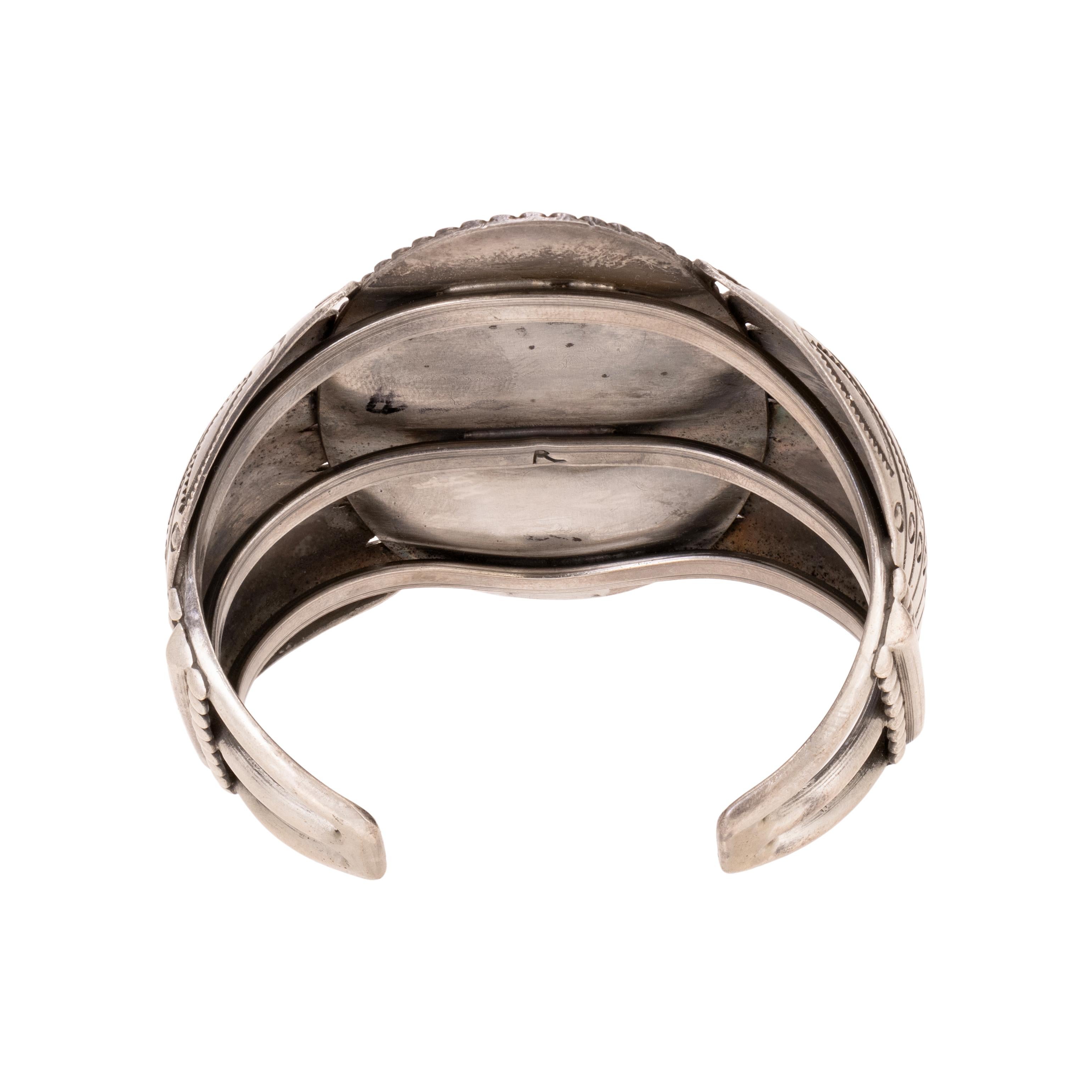 Pulsera brazalete de plata de ley con turquesa y coral de Kingman. Dos excepcionales piedras de turquesa Morenci engastadas en una cara de estilo shadowbox con coral en el centro, rodeadas de cuentas de plata esterlina y borde de cuerda retorcida.